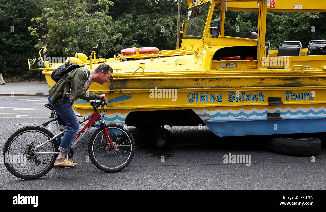 Un ciclista si ferma a guardare un Viking Splash Tour bus si trova al di fuori del Shelbourne Hotel in St. Stephen's Green a Dublino dopo una delle ruote è venuto fuori. Foto Stock