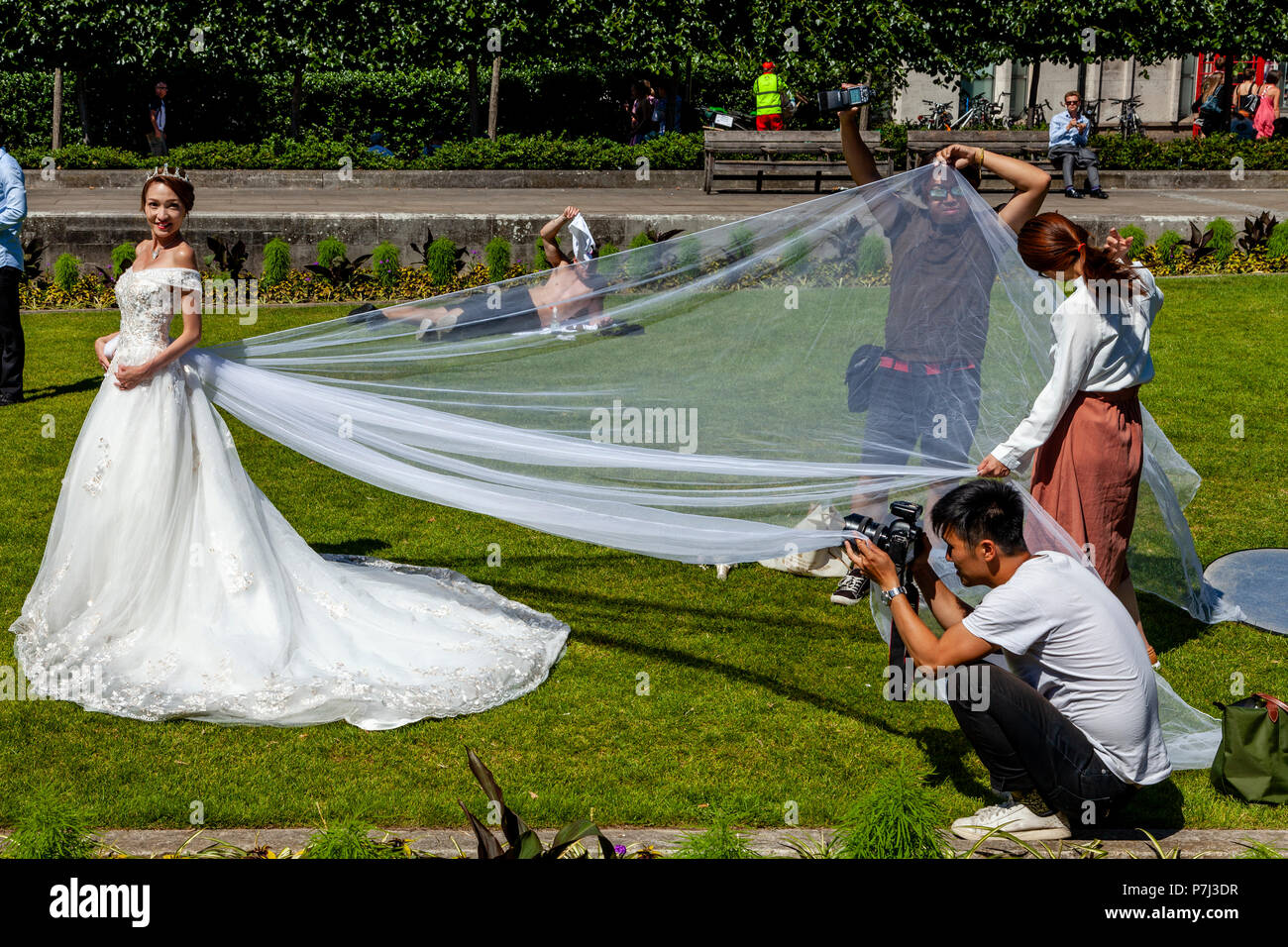 Una visita di sposa da Hong Kong pone per la fotografia di matrimonio sui prati fuori dalla cattedrale di St Paul, Londra, Inghilterra Foto Stock