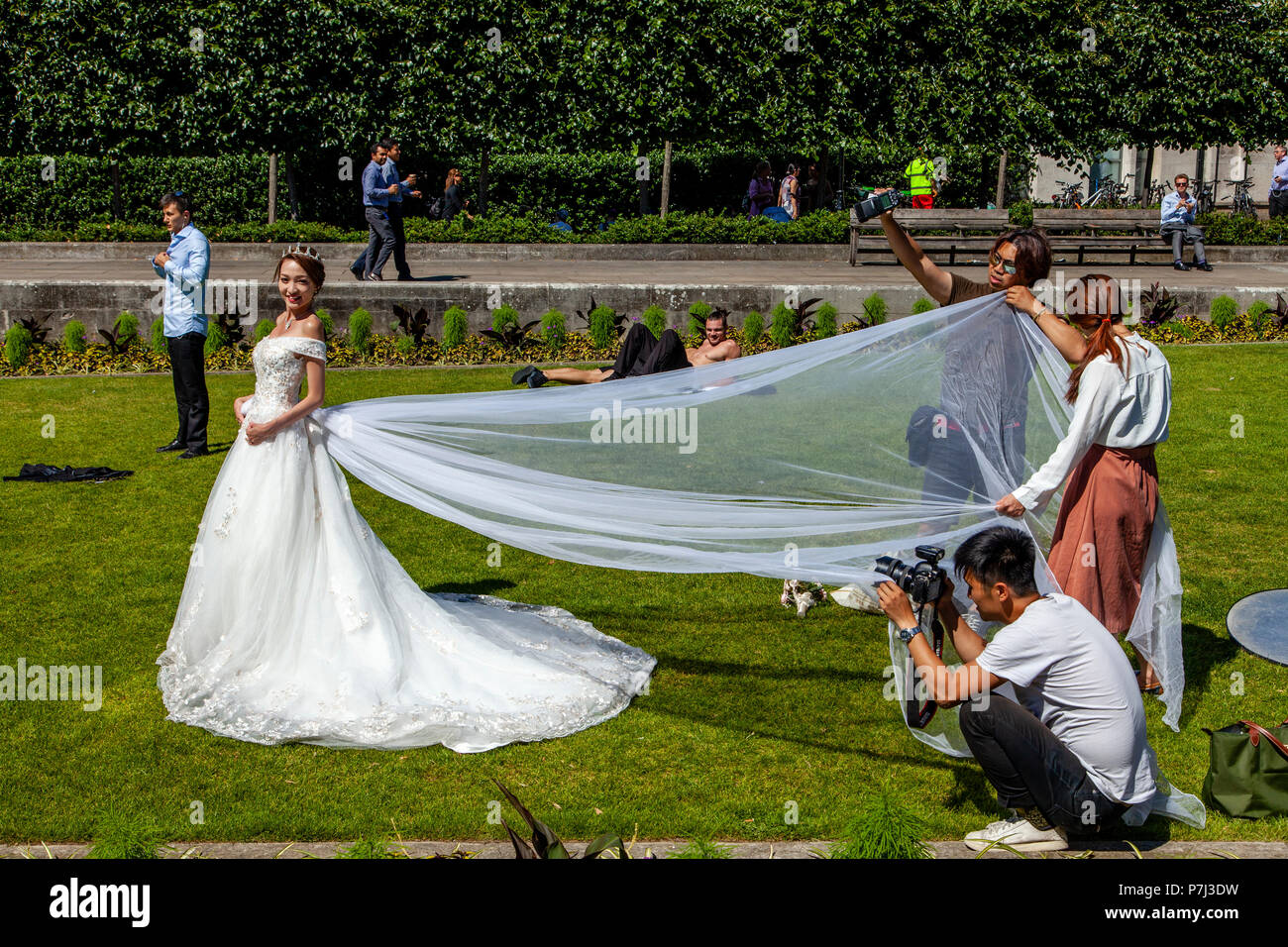 Una visita di sposa da Hong Kong pone per la fotografia di matrimonio sui prati fuori dalla cattedrale di St Paul, Londra, Inghilterra Foto Stock