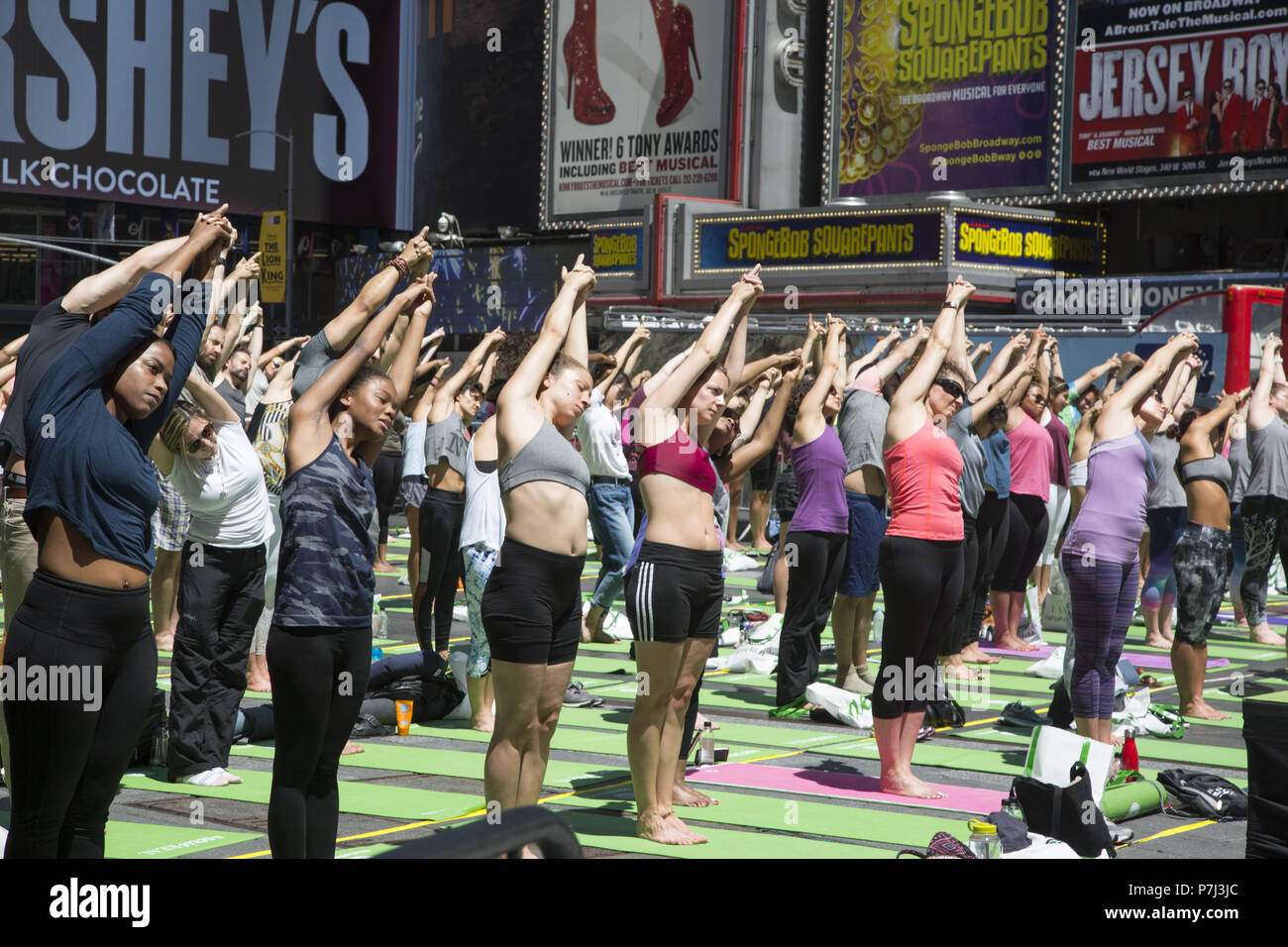 Gli appassionati di Yoga prendere lezioni gratuite nell'annuale Times Square solstizio d estate la celebrazione con le classi per tutta la giornata in mezzo al materiale sfarzo del quartiere di New York City. Foto Stock