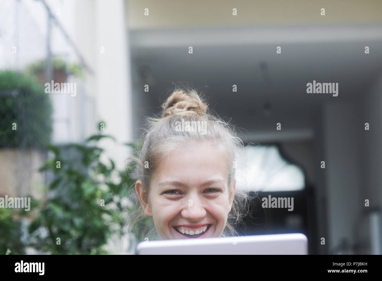 Donna sorridente seduti all'aperto utilizzando una tavoletta digitale Foto Stock