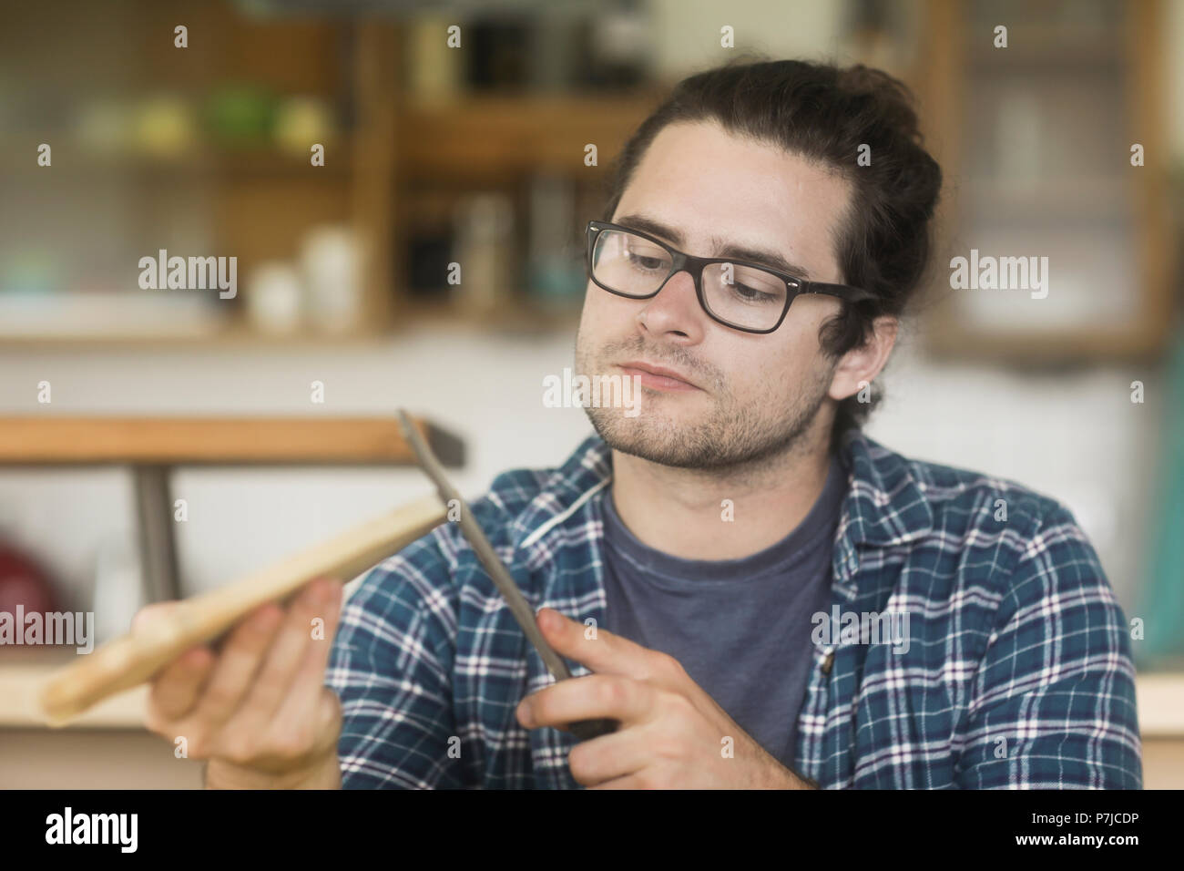 Uomo seduto in soggiorno rendendo un tagliere di legno Foto Stock