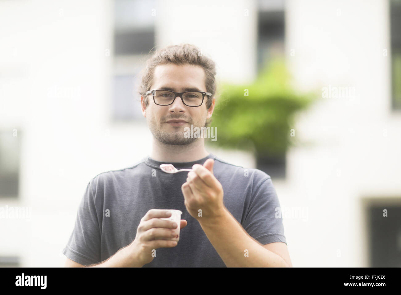 Uomo in piedi all'aperto di mangiare uno yogurt Foto Stock
