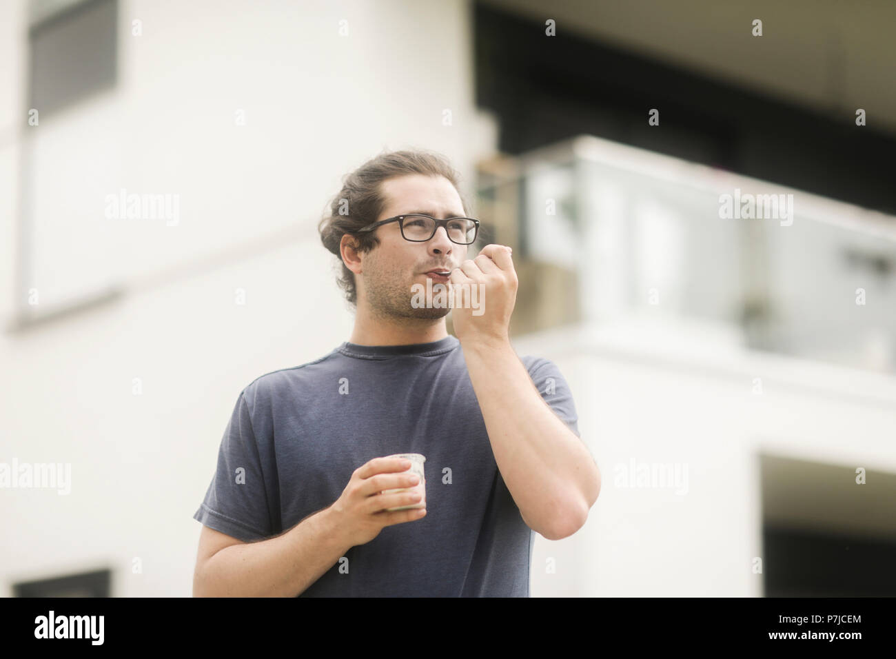 Uomo in piedi all'aperto di mangiare uno yogurt Foto Stock