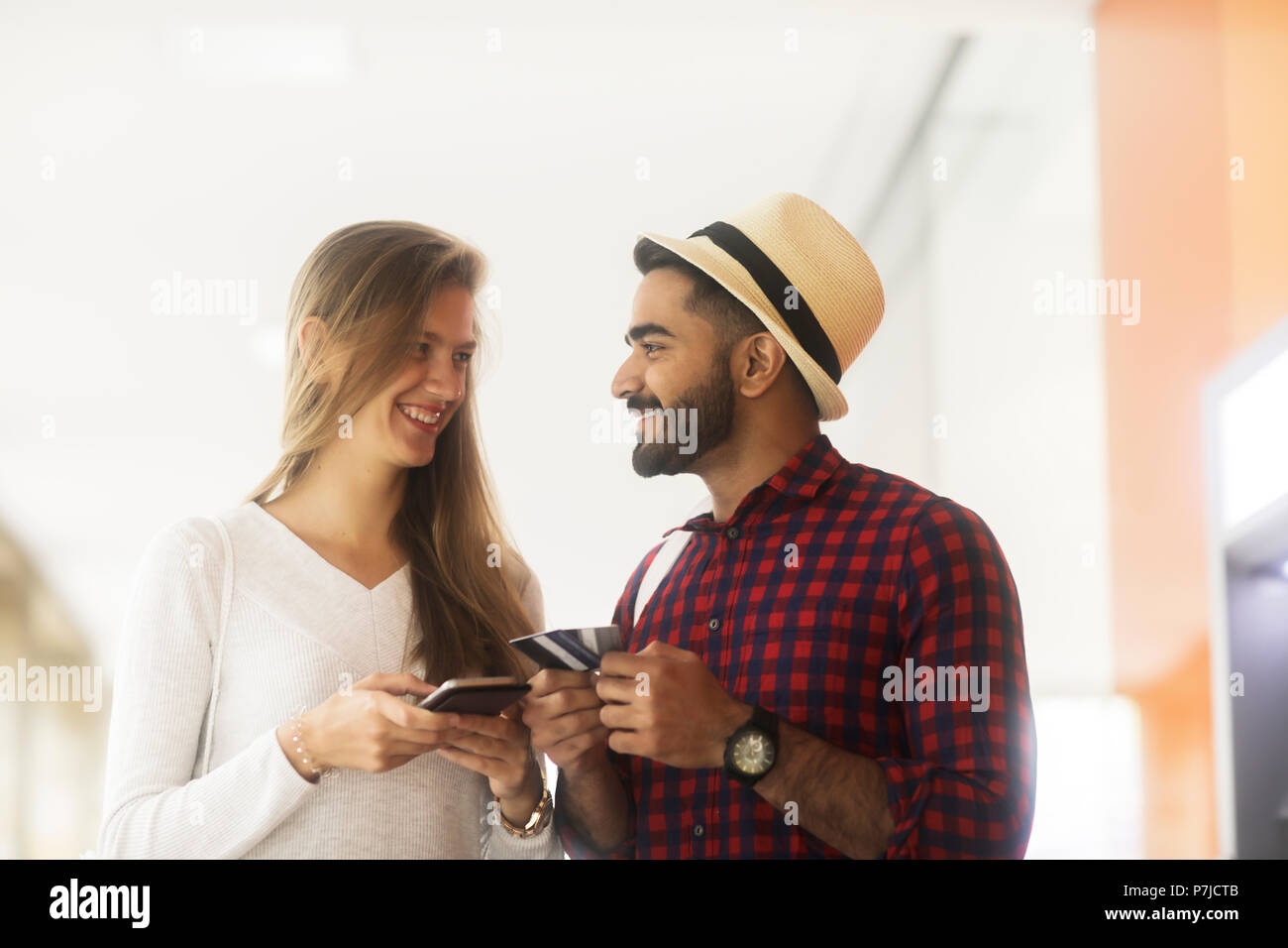 Ritratto di un sorridente giovane azienda di carte di credito e utilizzo di un telefono cellulare Foto Stock