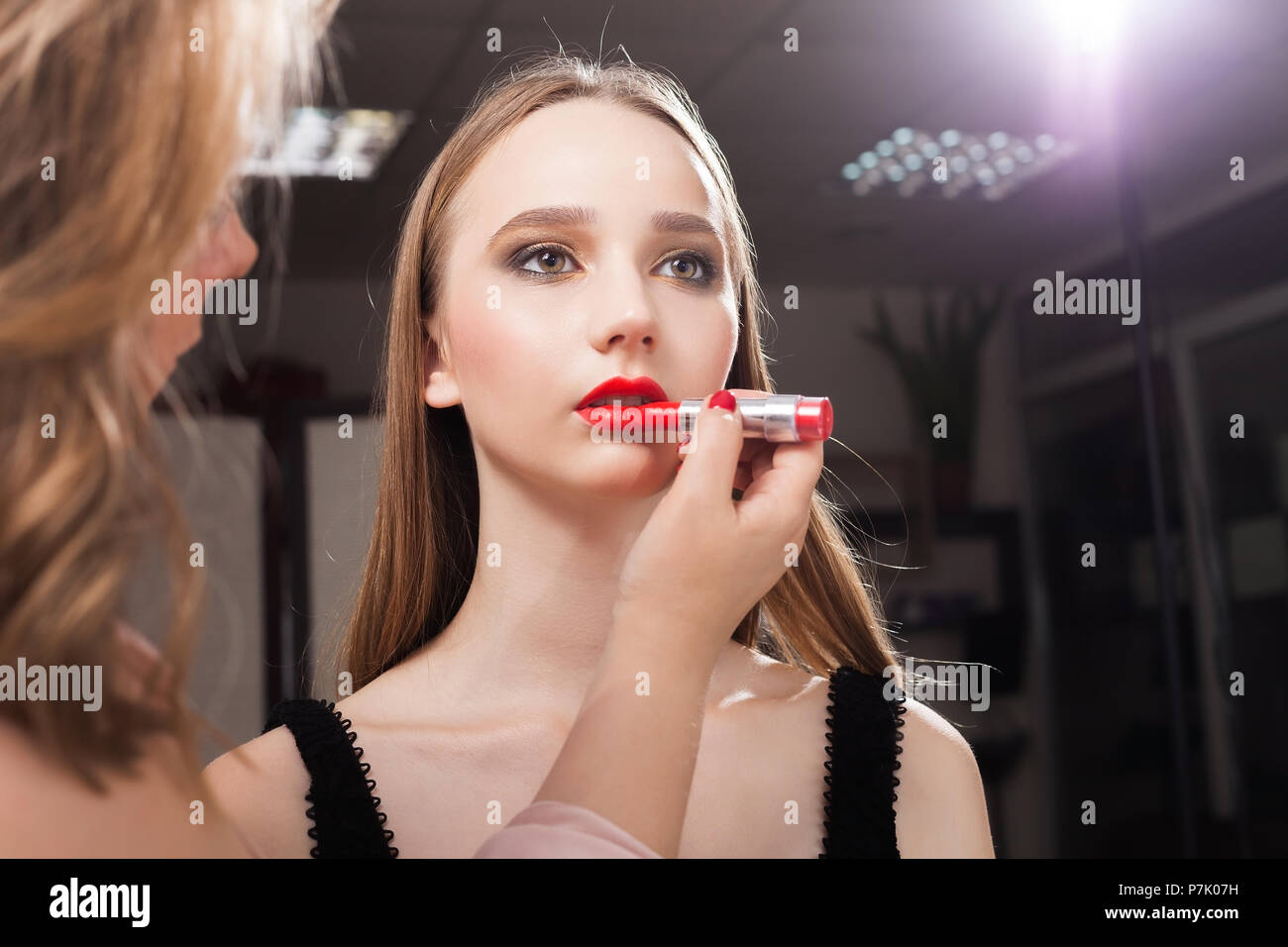 Trucco donna l'applicazione red lip gloss su un modello Foto Stock