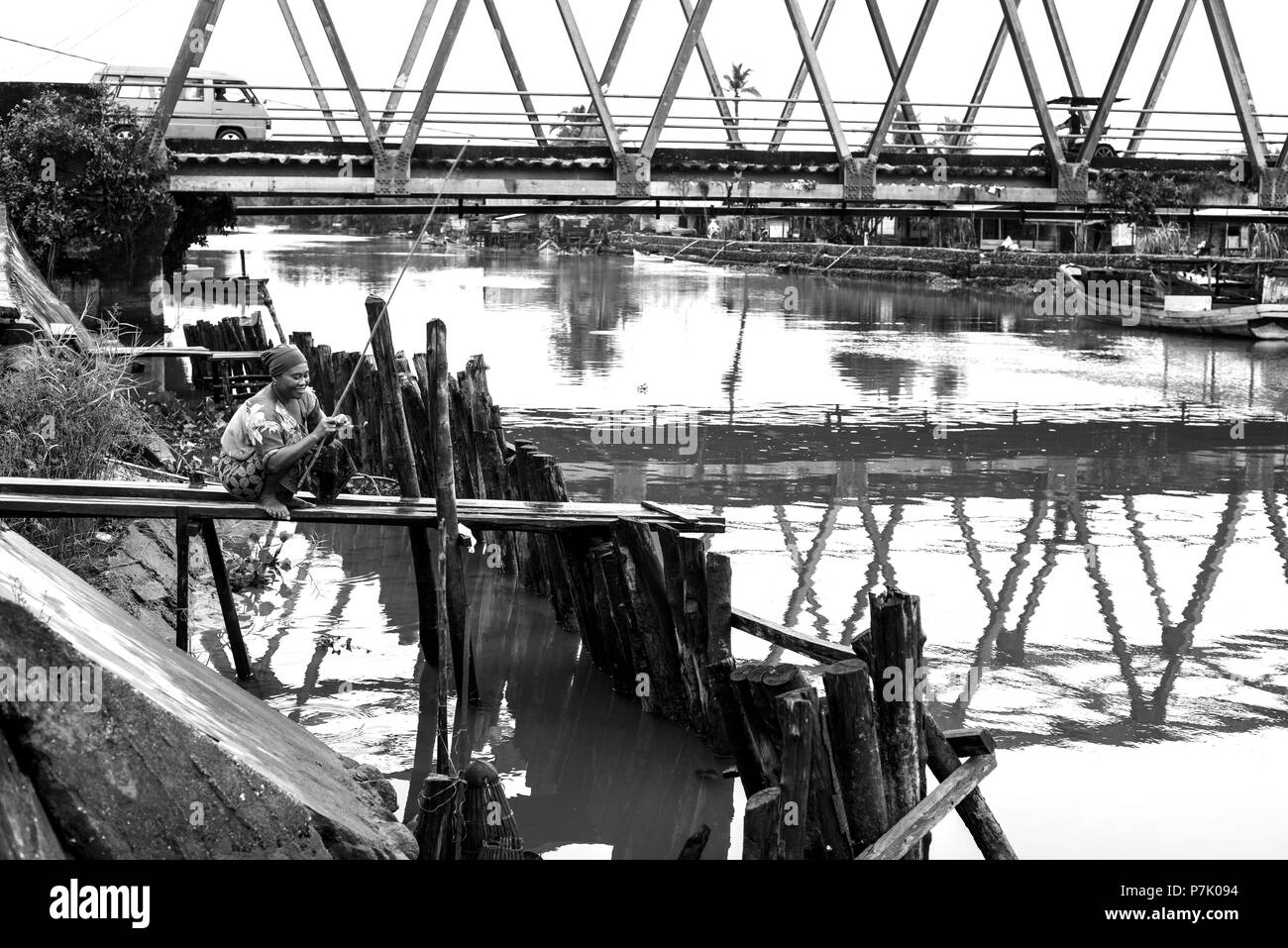 Un fisherwoman cattura di pesci piccoli come esca per suo marito, che più tardi vuole la cattura di pesci grossi con loro, lei è seduta e ridere su di un piccolo molo sul lungomare, Foto Stock