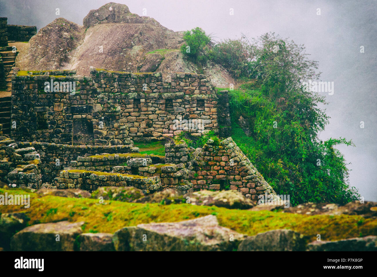 Nuvole dietro un enorme pietra e rovine storiche della città perduta nella natura del Machu Picchu. Il Perù. N. persone. Foto Stock