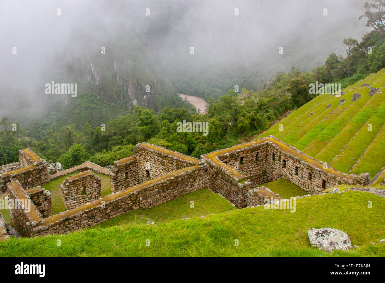 Bellissimo paesaggio fotografico di antica costruzione e verdi campi su una scogliera con un rosso acqua flusso del fiume della valle. Machu Picchu. N. persone. Foto Stock