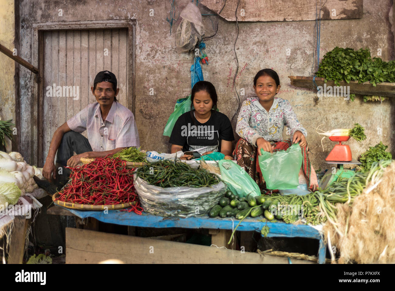Una famiglia vendere verdure al loro mercato in stallo Foto Stock