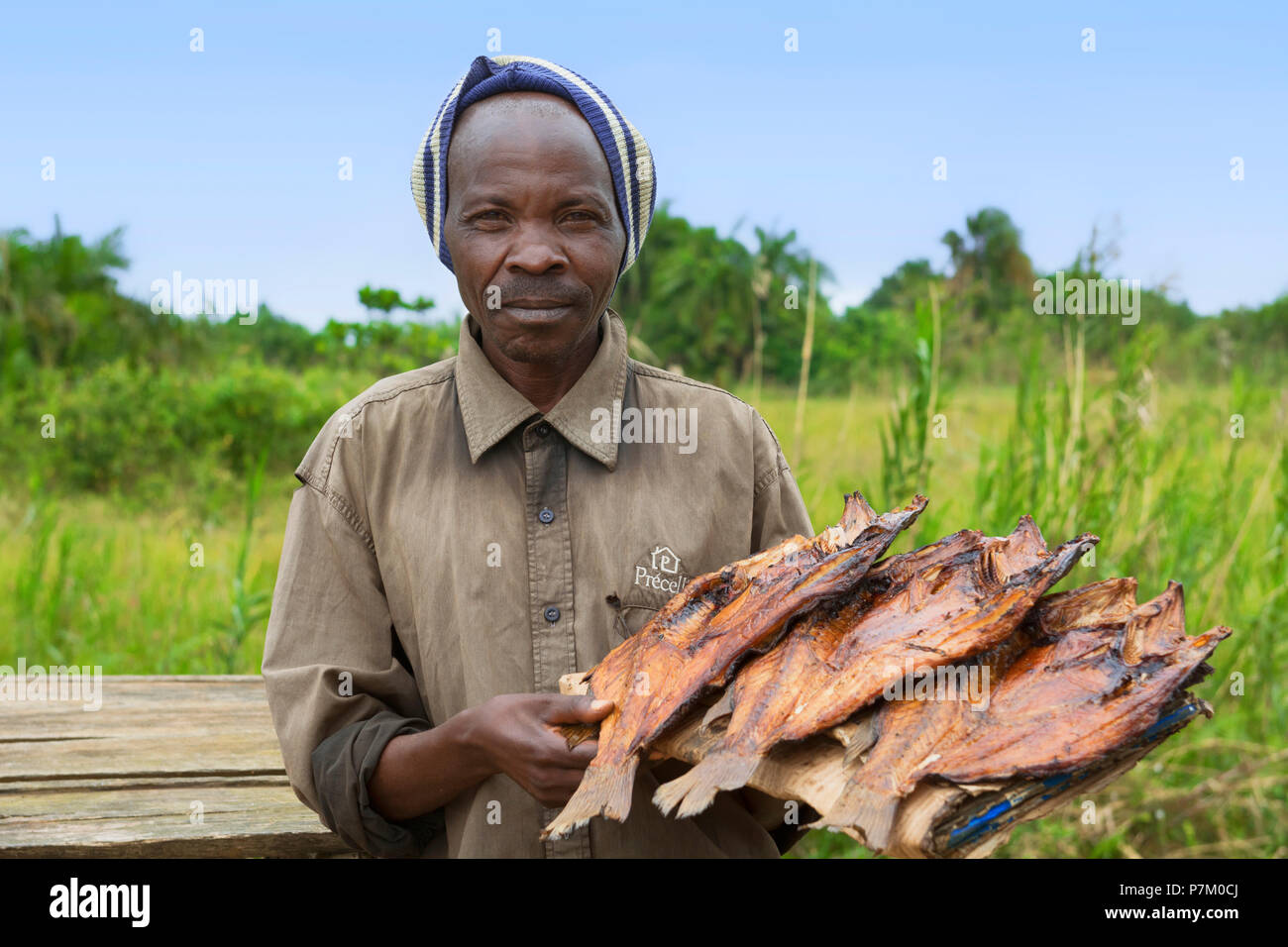 Fumato Tilapia, Ngege, uomo ugandese di vendita del pesce al bordo della strada, venditore ambulante, Uganda, Africa orientale Foto Stock