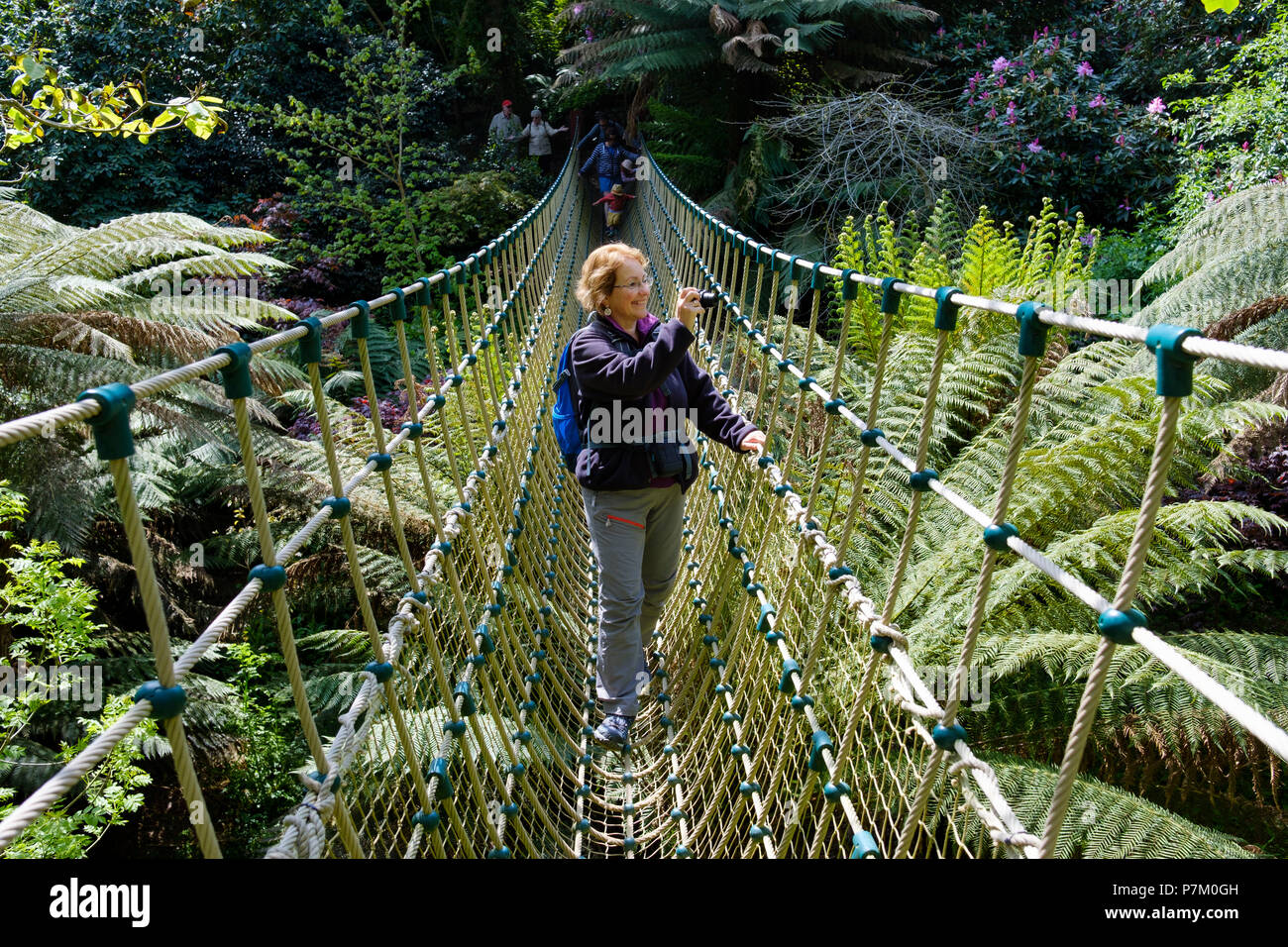 Donna sulla Birmania ponte di sospensione nella giungla, il Lost Gardens of Heligan, a St Austell, Cornwall, England, Regno Unito Foto Stock