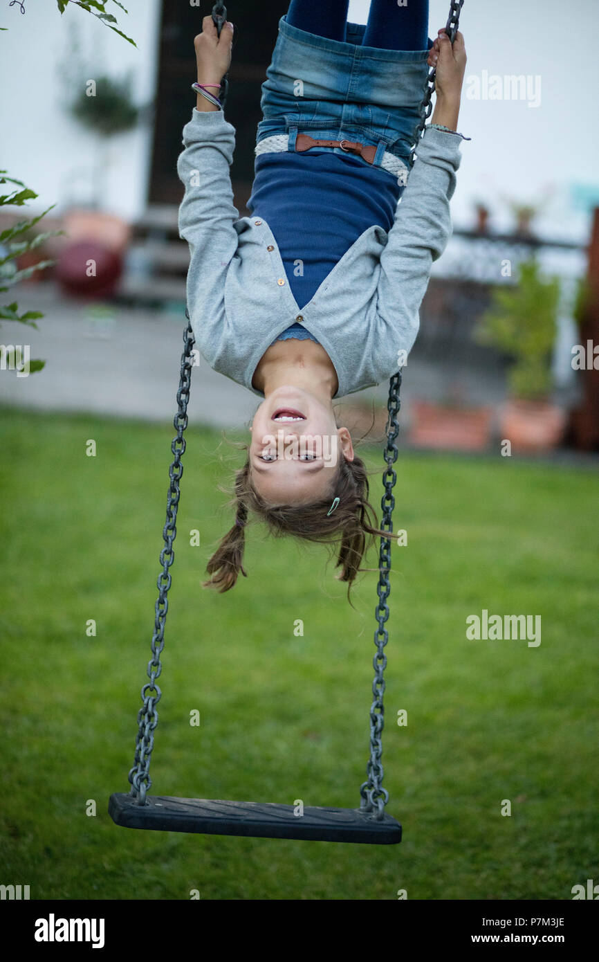 Ragazza appeso a testa in giù su un altalena nel giardino Foto stock - Alamy