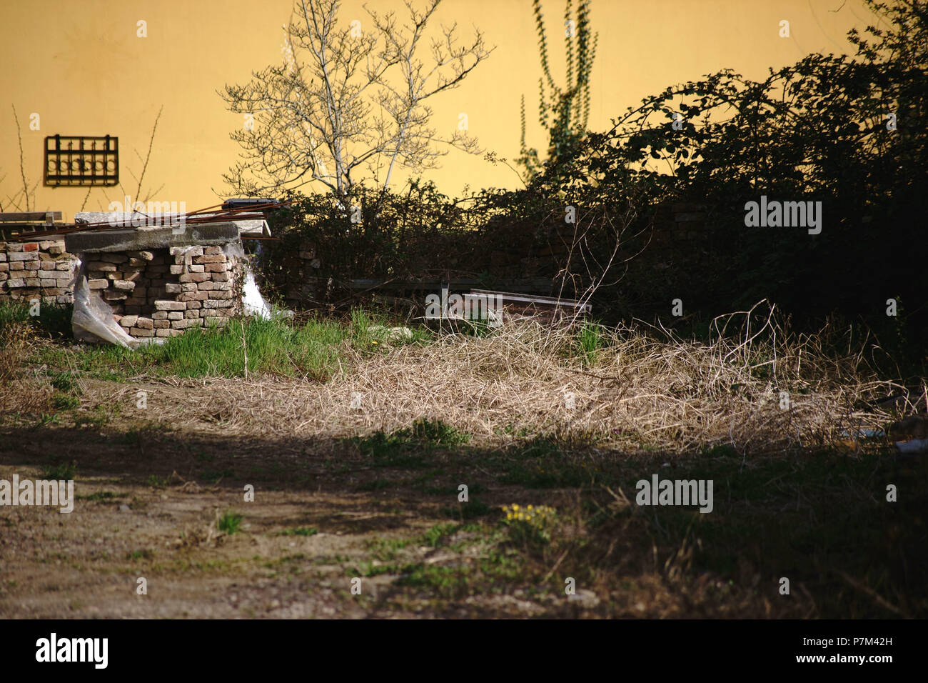 Un rustico e nostalgico il cortile interno con le pile di mattoni e boccole sovradimensionate. Foto Stock