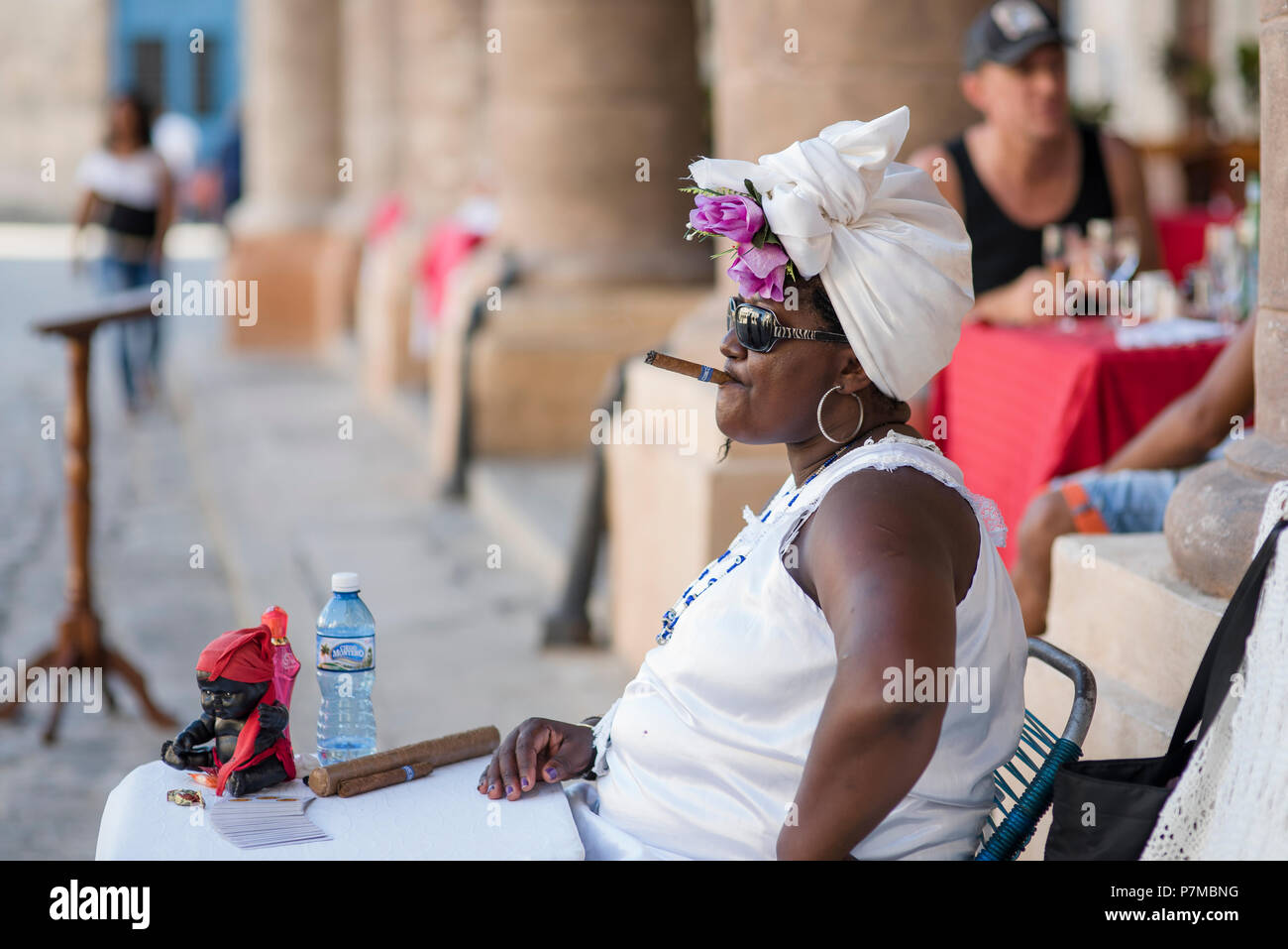 Teresa l'indovino di fumare un sigaro cubano e godersi il bel tempo in Plaza de la Catedral, Havana, Cuba. Foto Stock