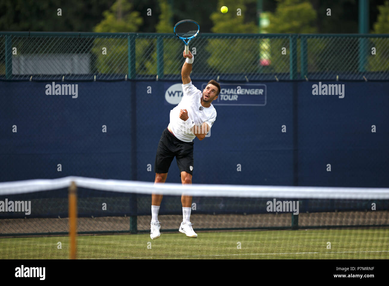 Professional Tennis servire, giocatore di tennis professionista che serve, Andres Artunedo Martinavarro nel mezzo di un servire durante una partita a una corte di erba torneo nel Regno Unito. Foto Stock