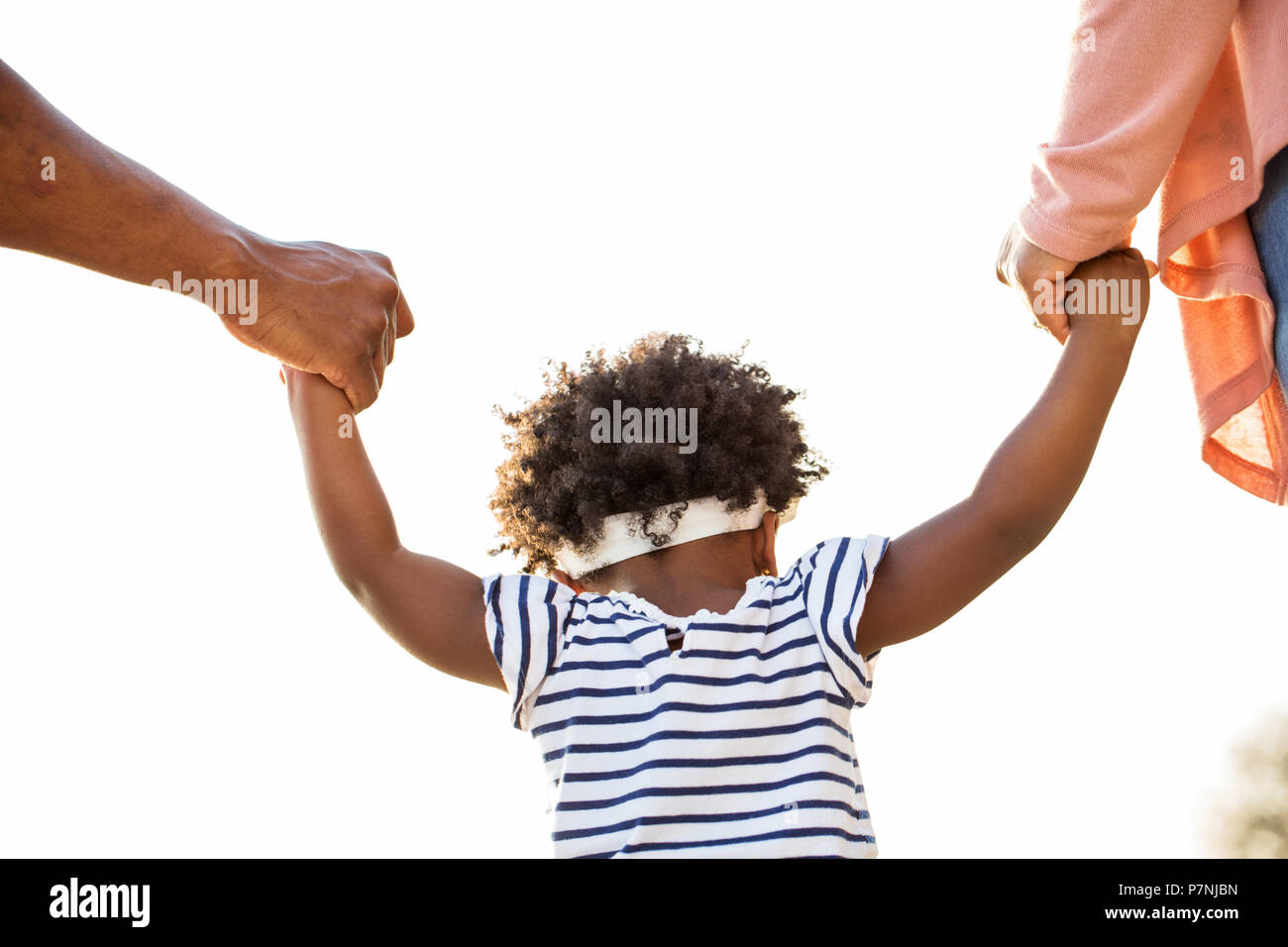 Bambina tenendo le mani con i suoi genitori. Foto Stock