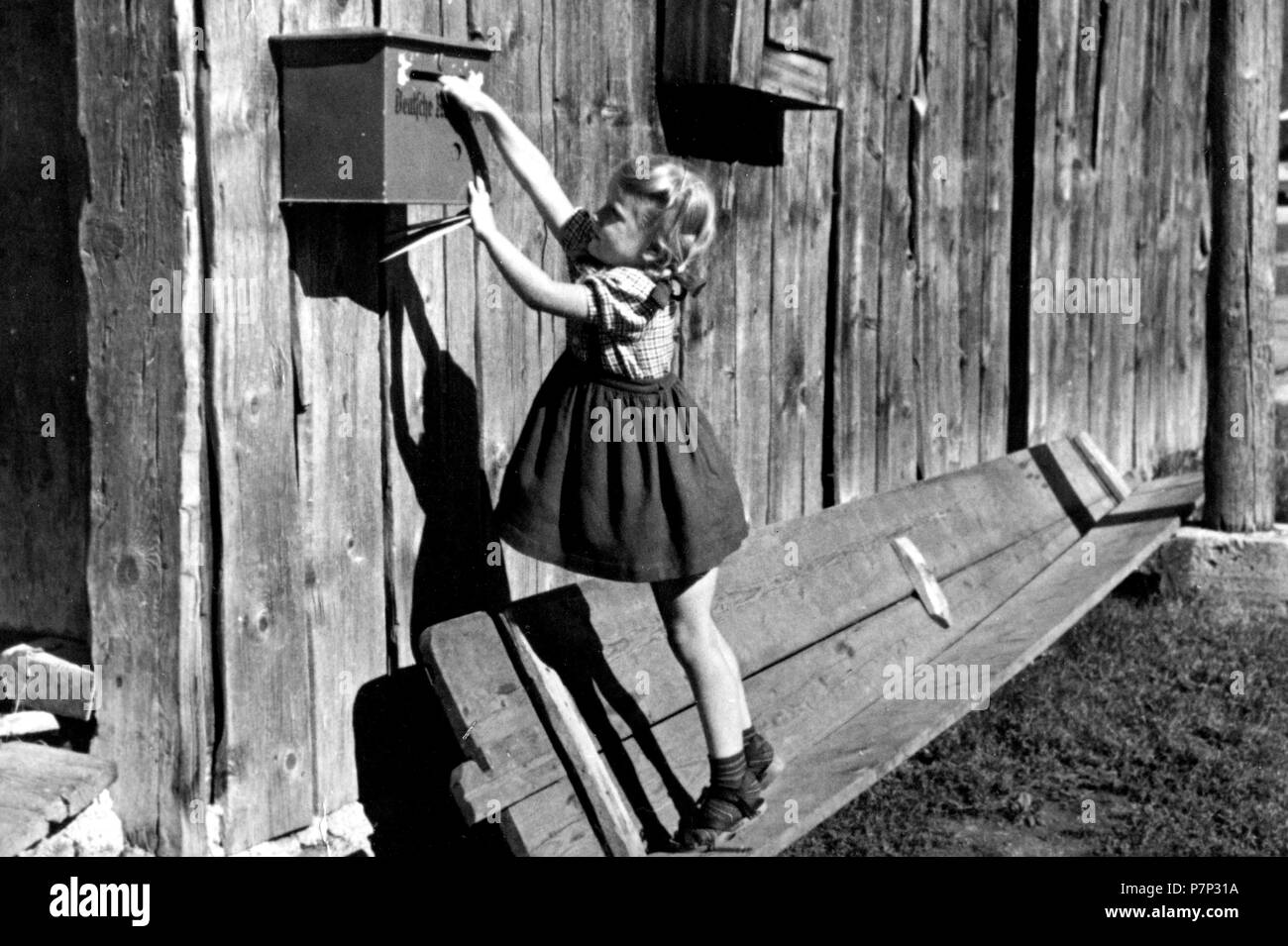 Ragazza nel tentativo di raggiungere la cassetta postale, ca. 1930, esatto luogo sconosciuto, Germania Foto Stock