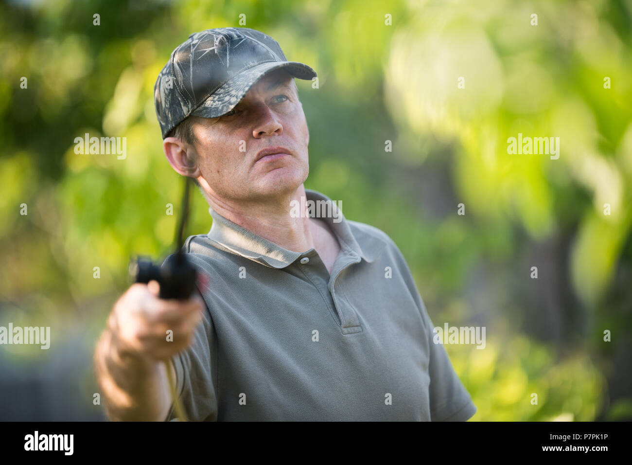 Giardiniere applicando un insetticida fertilizzante per il suo frutto arbusti, servendosi di uno spruzzatore Foto Stock