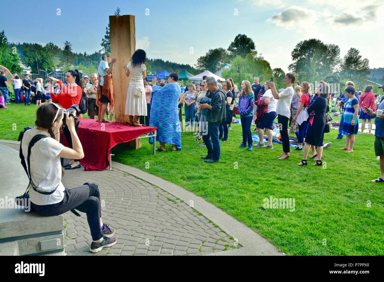 Aboriginal Carver, James Harry e sostenitori presenta il suo nuovo totem per il pubblico. Girato dal palco della prospettiva al PCT, Port Moody, BC Canada Foto Stock