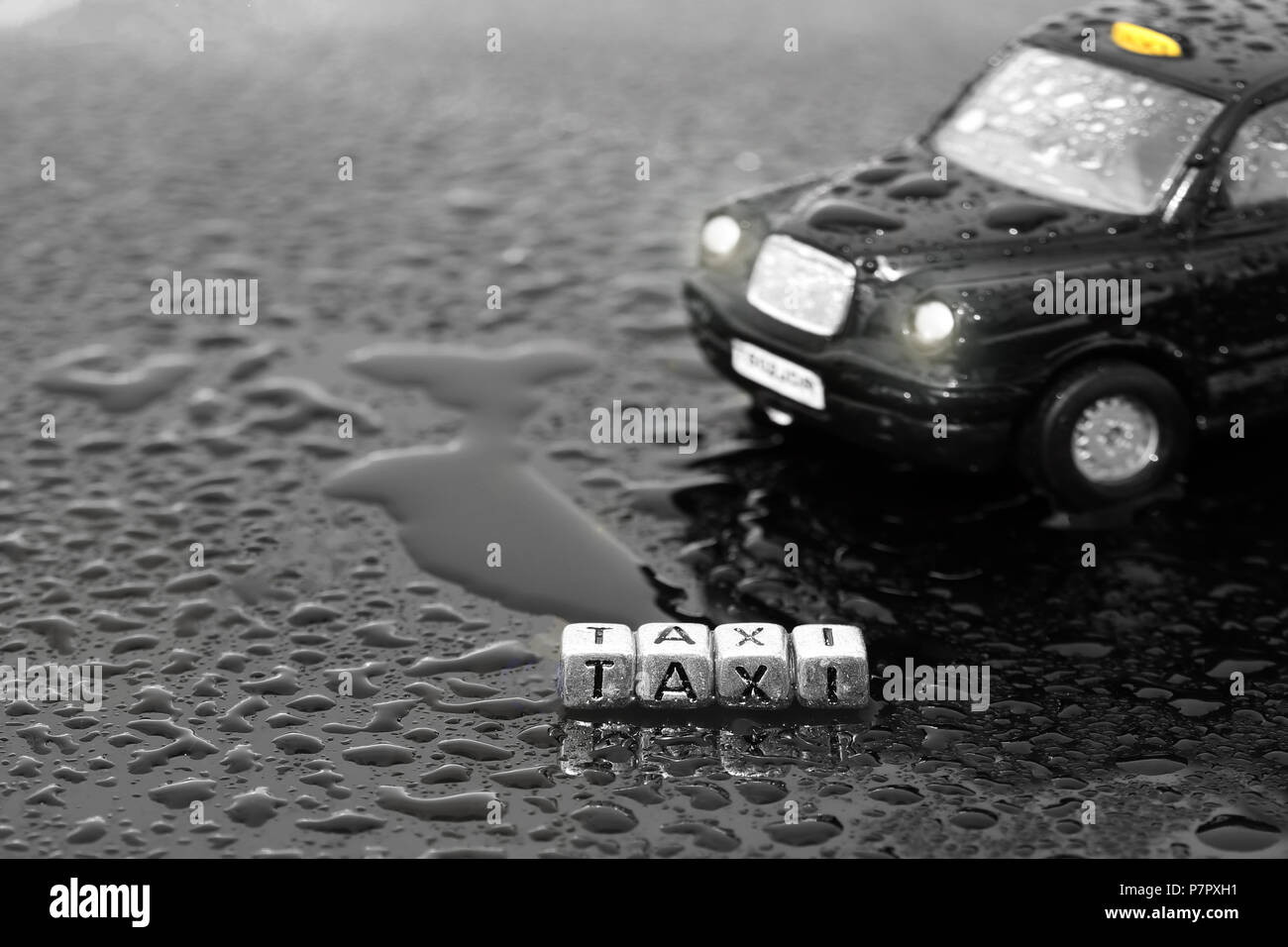 Tradizionale britannico black cab taxi auto giocattolo con la parola taxi su talloni sul bagnato Foto Stock
