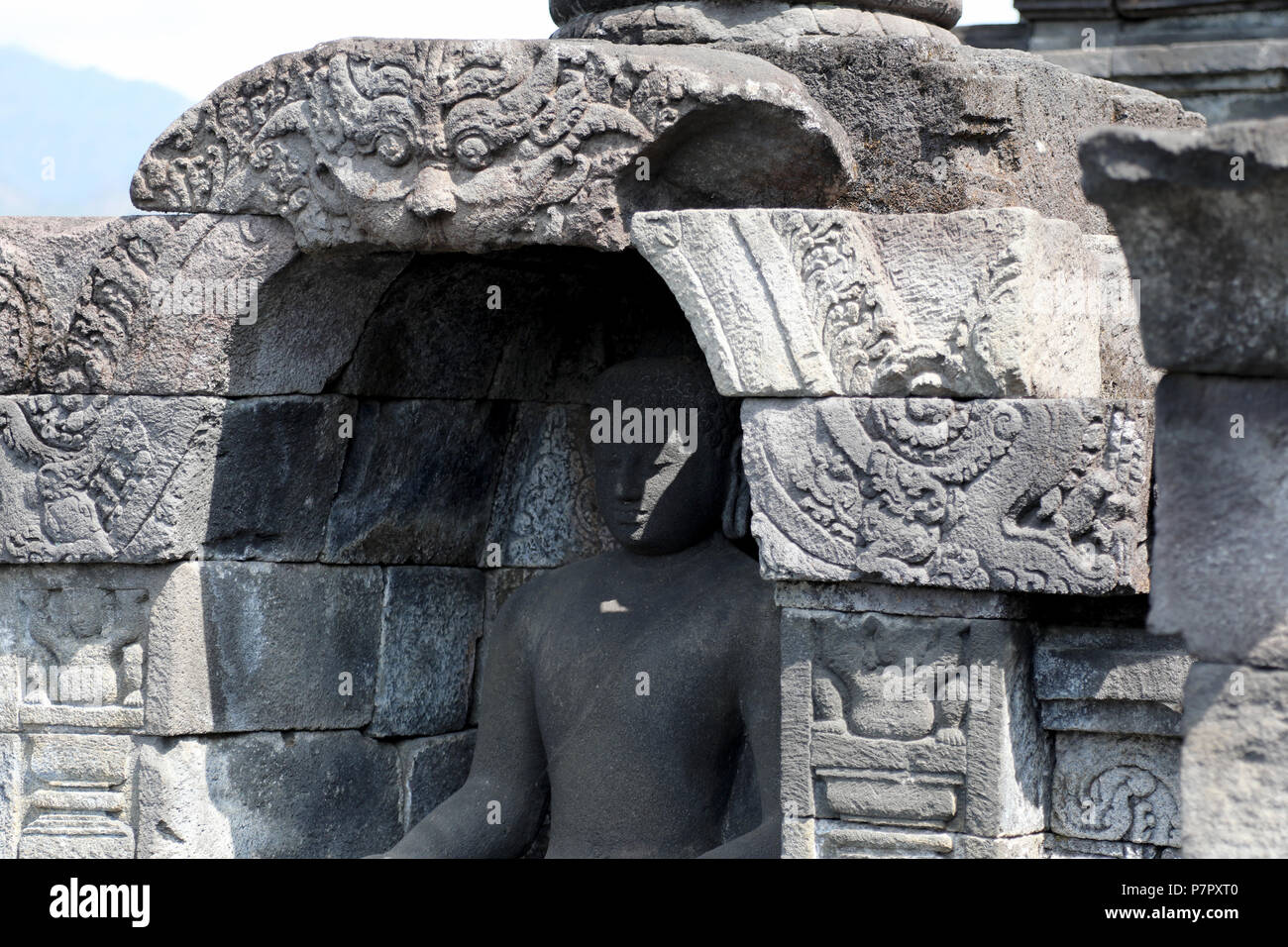 Borobudur, Indonesia - 23 Giugno 2018: un albero di luce attraversa il volto di una statua del Buddha al tempio buddista di Tempio di Borobudur, nei pressi di Jogjakarta Foto Stock
