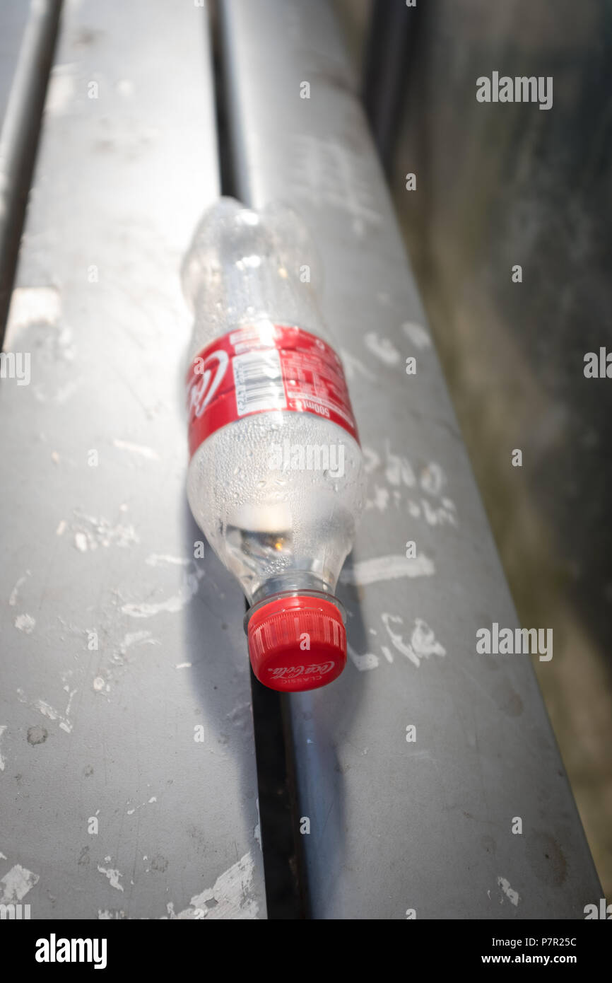 Di plastica vuote Coca Cola bottiglia abbandonato in un bus shelter. Foto Stock