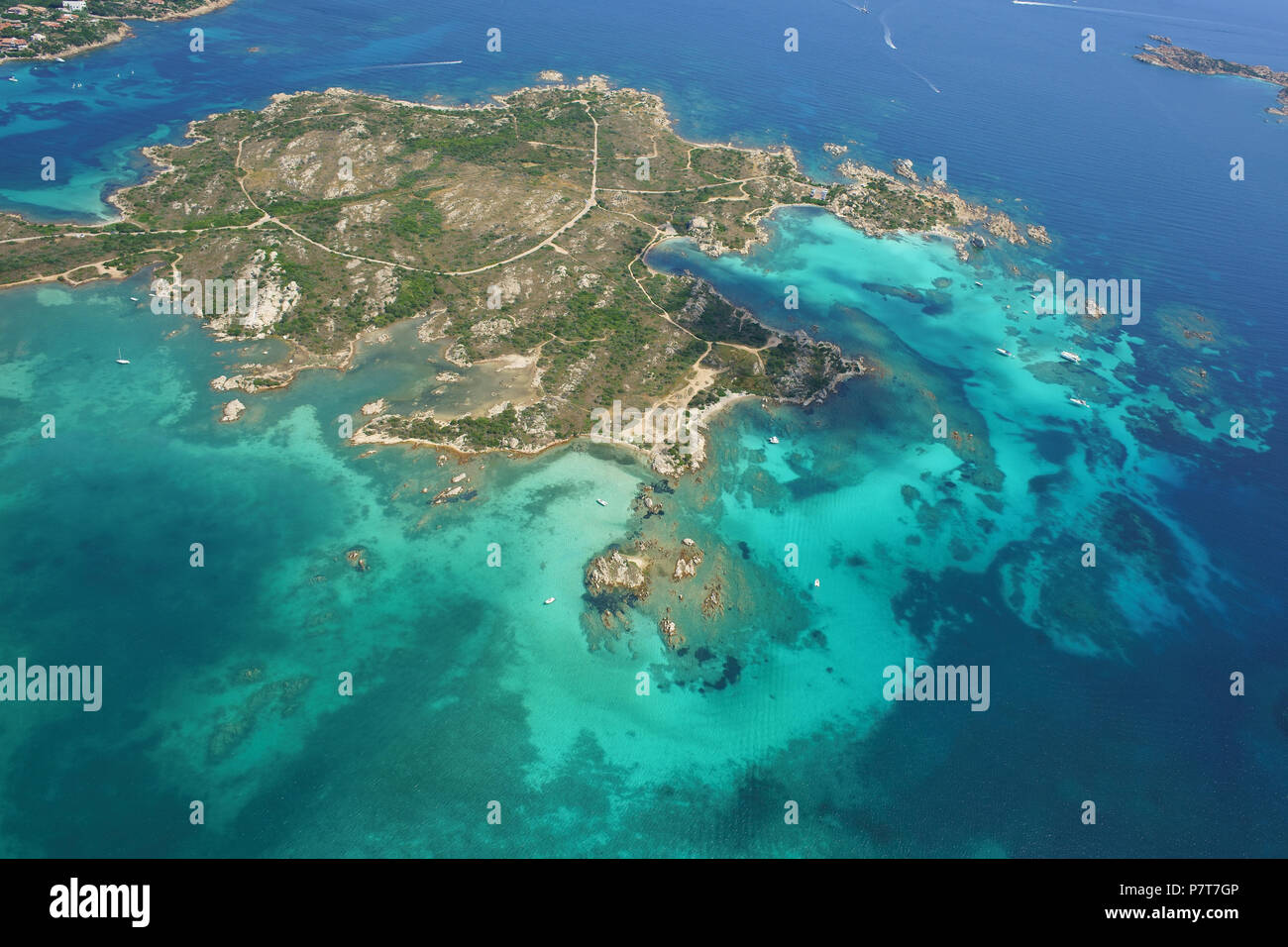 VISTA AEREA. Isola disabitata circondata da acque turchesi. Isola dei Giardini, Arcipelago la Maddalena, Provincia di Sassari, Sardegna, Italia. Foto Stock