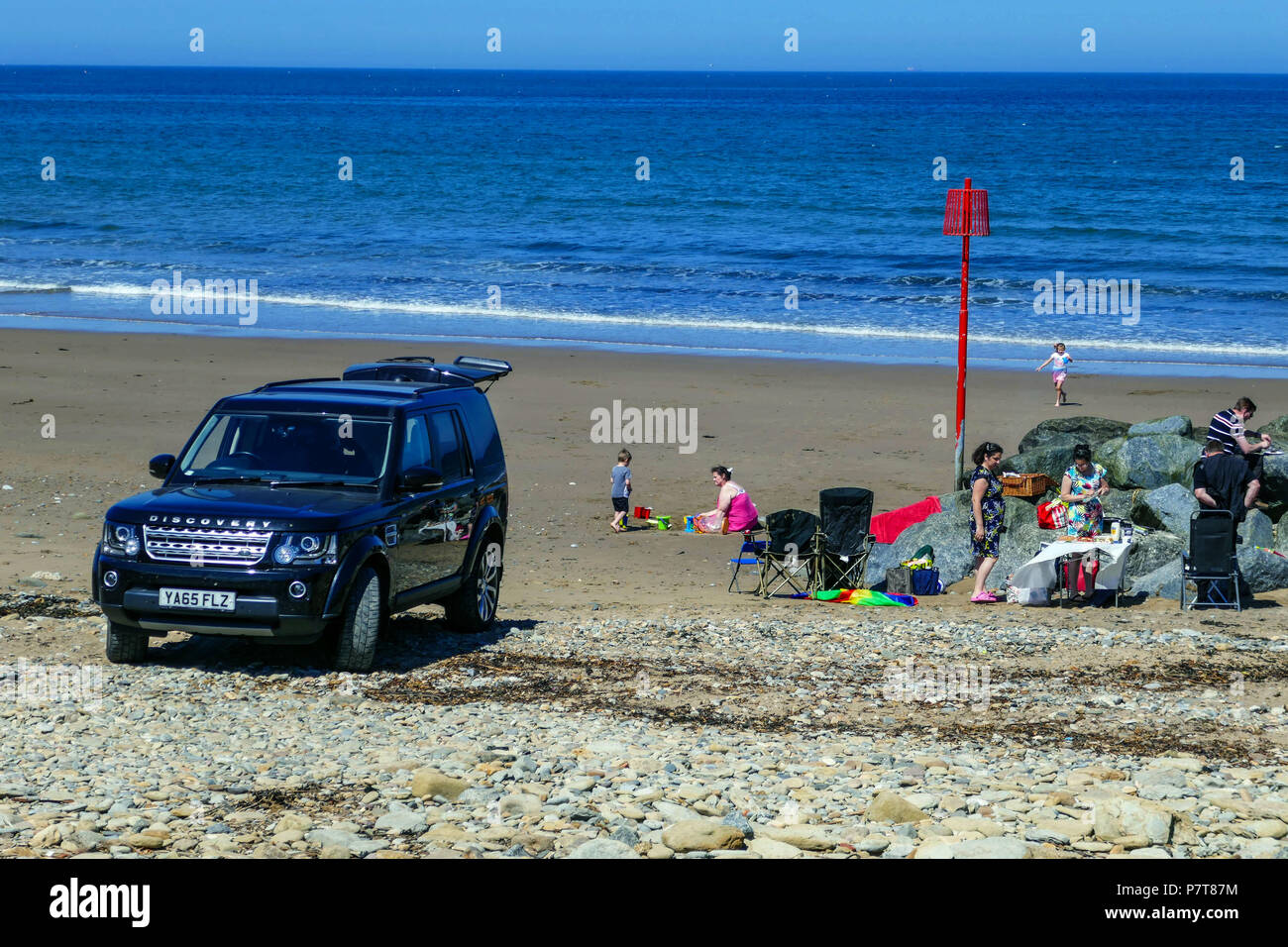 Auto sulla spiaggia con picnic in famiglia, barbeque, barbecue, blu caldo giorno d'estate come cittadina balneare di Skinningrove, North Yorkshire Foto Stock