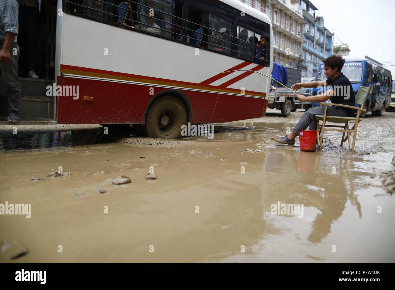 Kathmandu, Nepal. 8 Luglio, 2018. Un arts studente esegue la simulazione di pesca come una dimostrazione contro la gravemente danneggiato road a Boudha a Kathmandu, Nepal, domenica 08 luglio, 2018. Esso è stato anni il governo ha trascurato la costruzione del tratto di strada da Boudha a Sankhu. Credito: Skanda Gautam/ZUMA filo/Alamy Live News Foto Stock