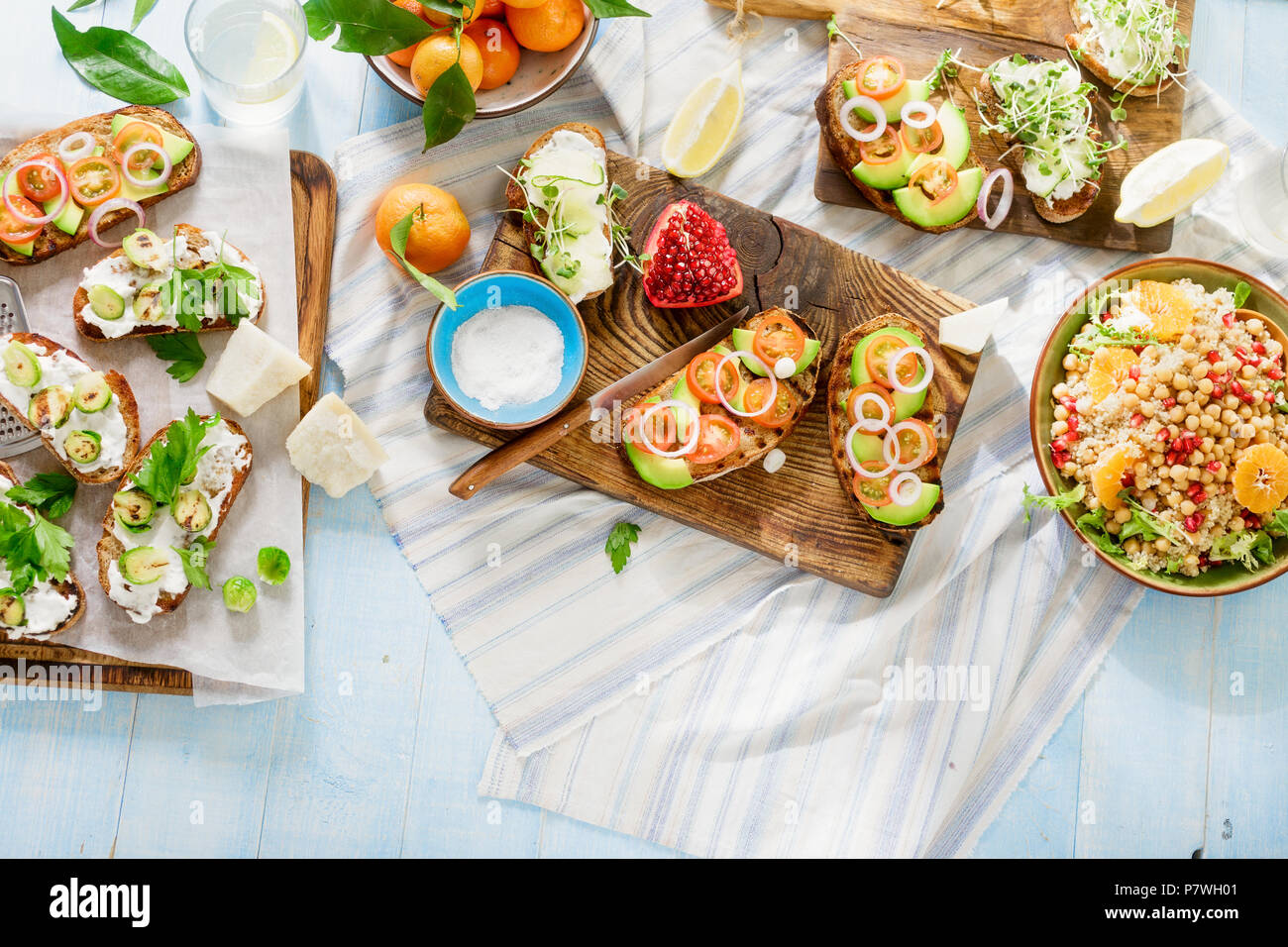 Set di piatti vegetariani su blu tavolo in legno con limonata fatta in casa. Bruschetta con pomodori, cetrioli, cavolini di Bruxelles e insalata con ceci una Foto Stock