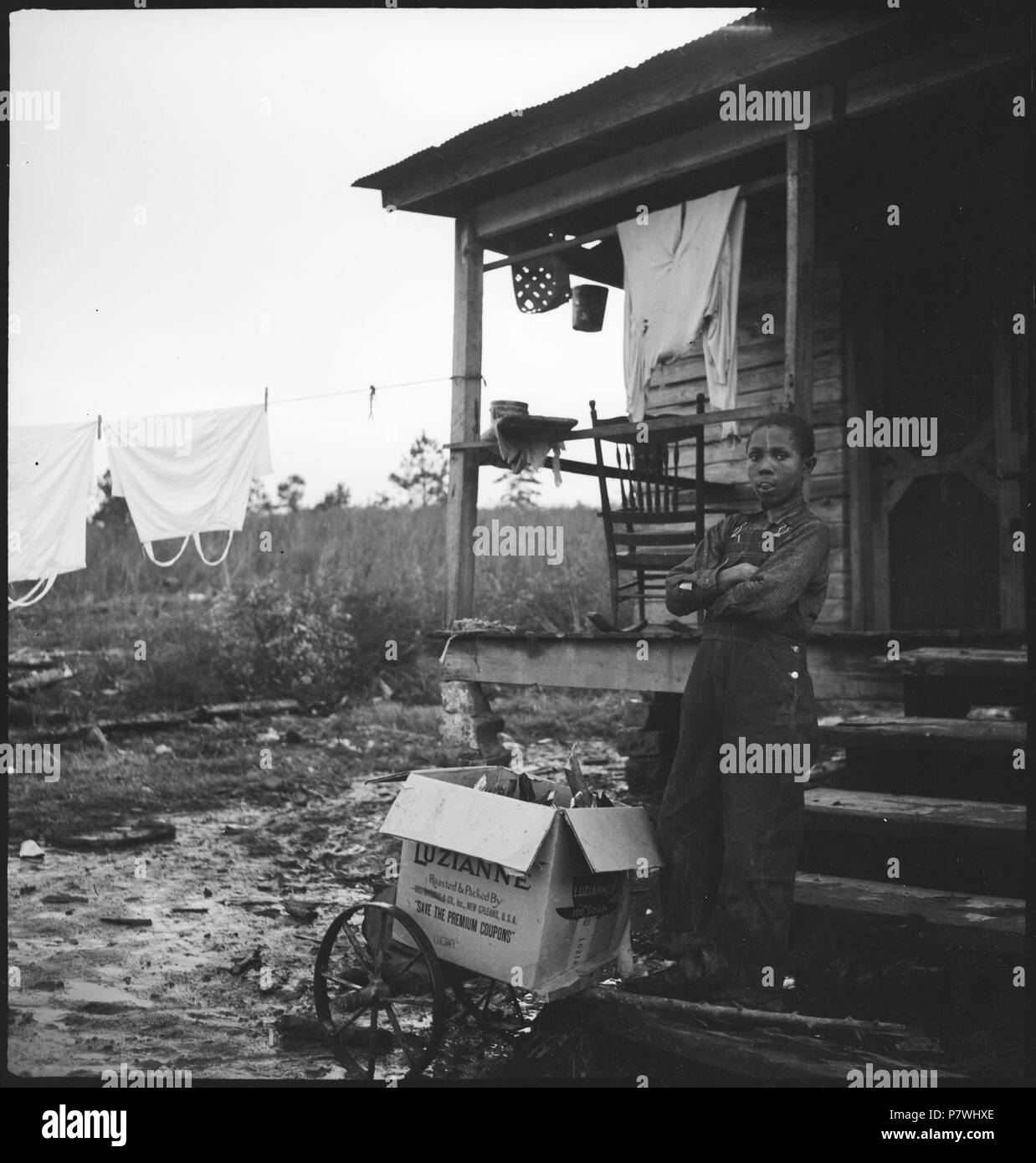 Stati Uniti d'America, nahe Columbus/GA: Menschen; EinJunge steht vor einer Holzhütte auf einer Treppe, auf einem Gefährt daneben eine Kartonkiste. Dal 1936 fino al 1938 86 CH-NB - USA, nahe Columbus-GA- Menschen - Annemarie Schwarzenbach - SLA-Schwarzenbach-UN-5-11-061 Foto Stock