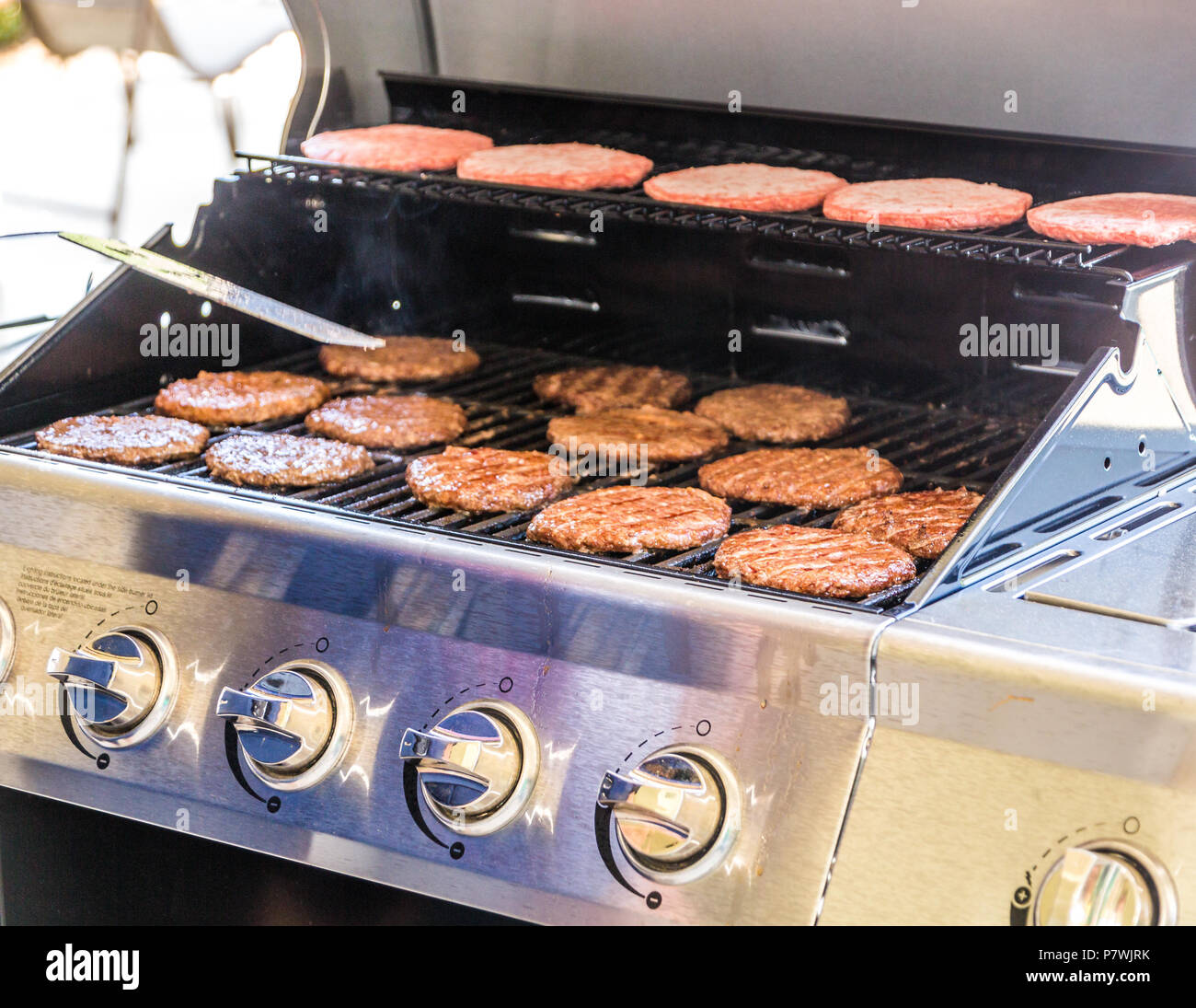 Ruotando gli hamburger sul grill Foto Stock