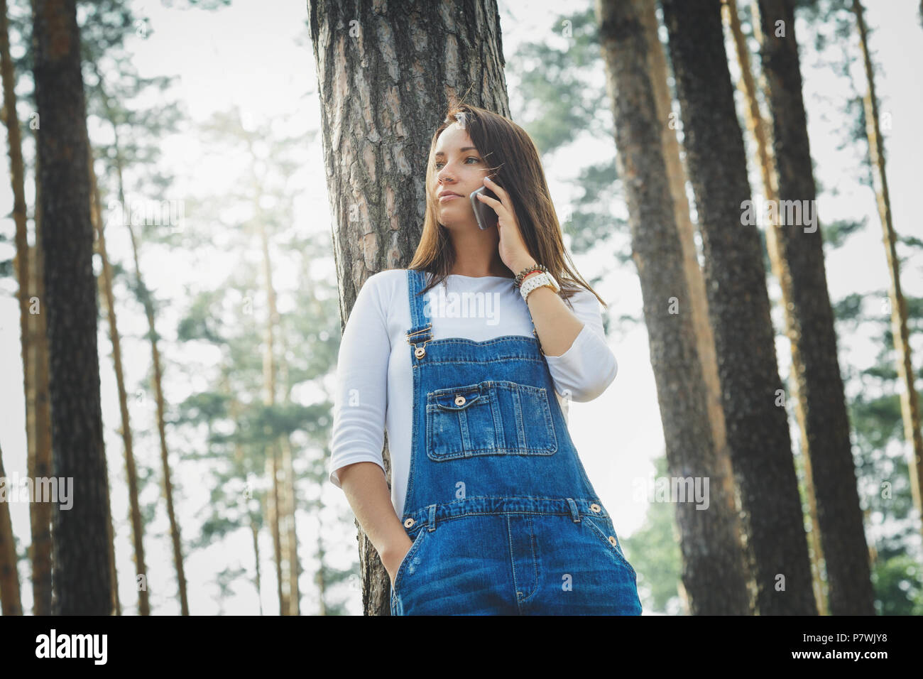 Bella giovane donna in tuta in jeans nella foresta Foto Stock