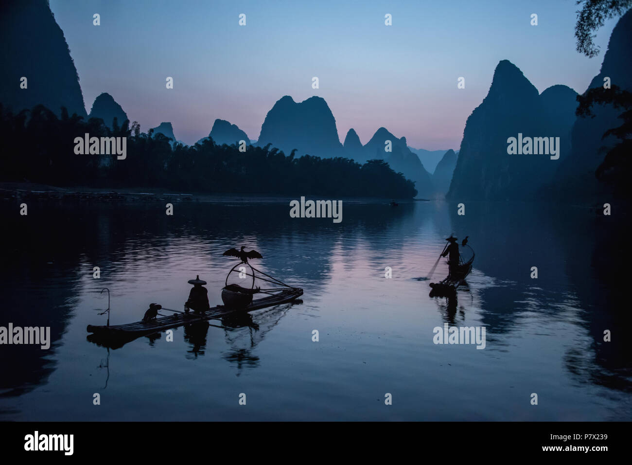 Cormorano pescatori pre-alba in un periodo tranquillo prima di iniziare a pescare, il Fiume Li, Cina Foto Stock