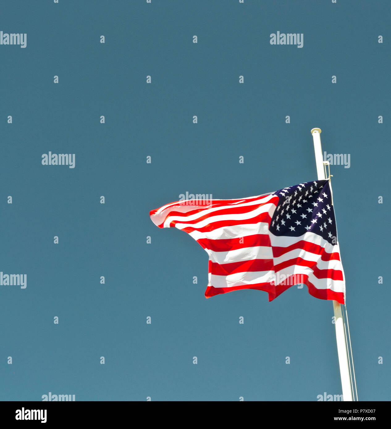Bandiera degli Stati Uniti sventolare nel vento con cielo blu come sfondo. Foto Stock