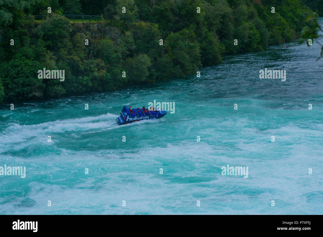 Cascate Huka Jet crociera in barca attraverso il fiume rapids con alberi e linea di bush in background in Taupo, Nuova Zelanda Foto Stock