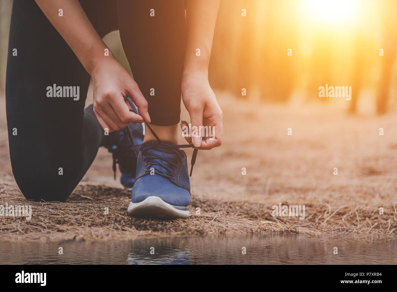 La donna occupare lacci delle scarpe quando jogging nella foresta di ritorno con acqua potabile bottiglia accanto a lei. Sneakers corda legatura. Persone e stili di vita del concetto. Healt Foto Stock