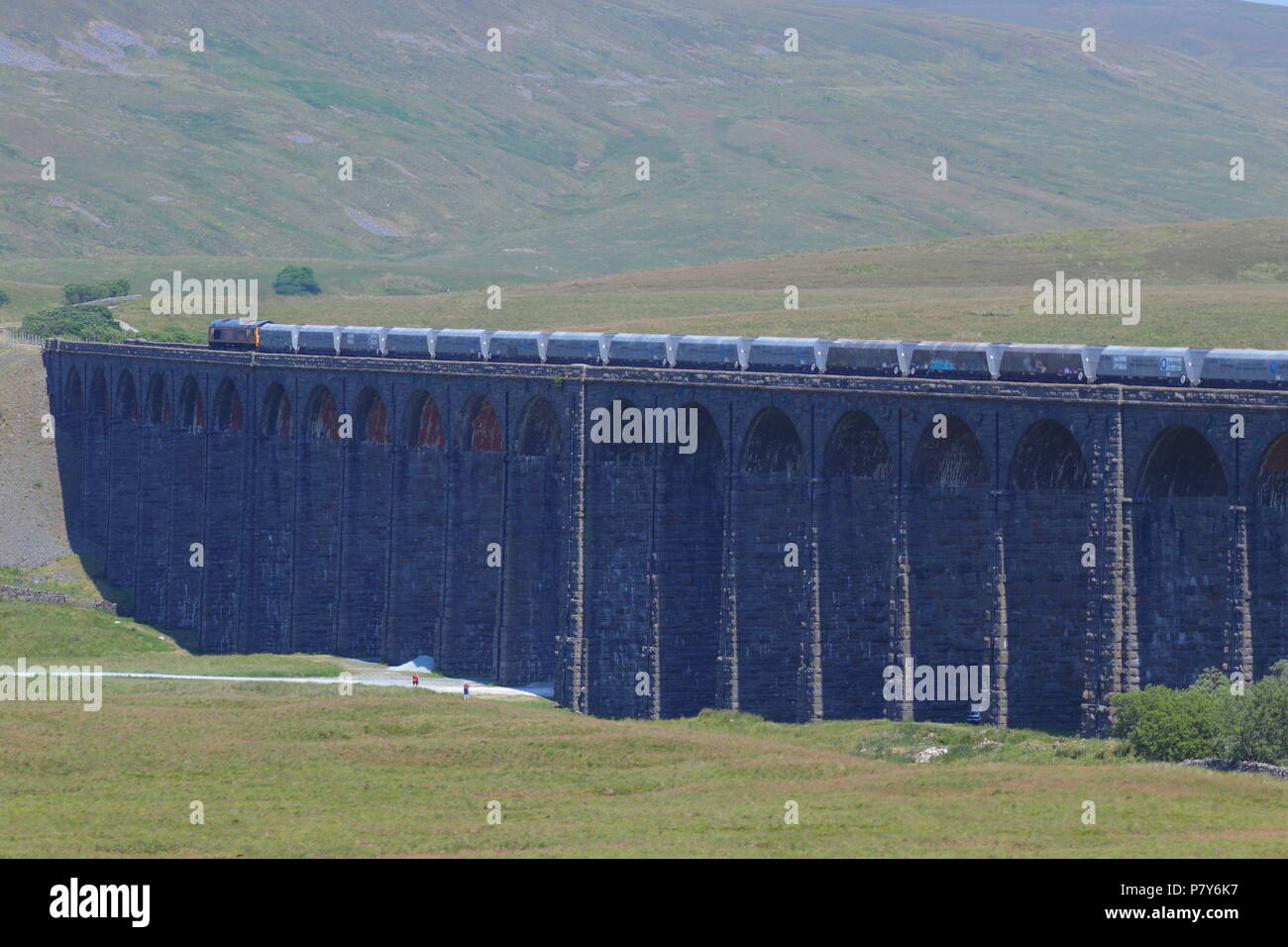 Un grande British Railway treno merci attraversa il possente e impressionante progettato in stile vittoriano viadotto Ribblehead ponte ferroviario nel Yorkshire Dales. Foto Stock