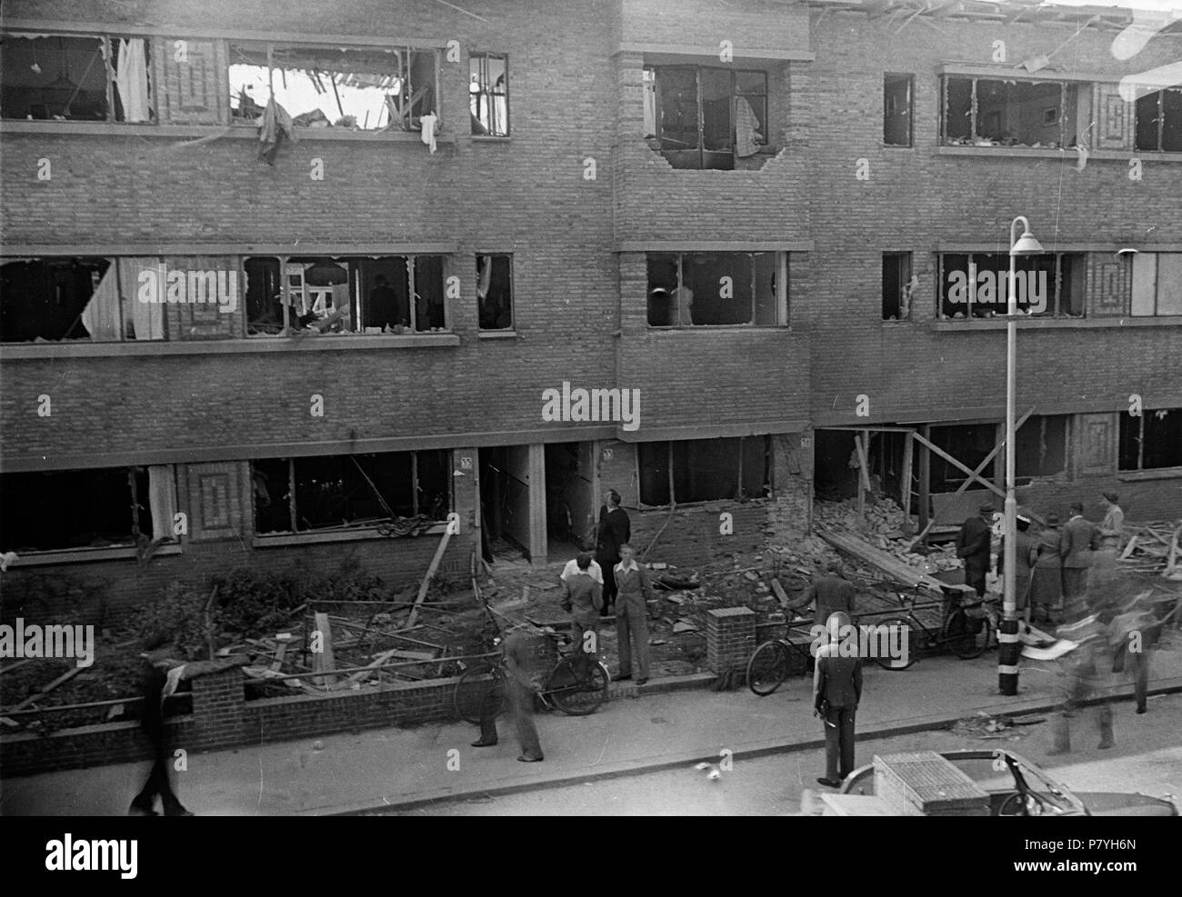 . Huizinga collectie V2 inslag - NIOD - 216553. Nederlands: Foto uit de collectie Huizinga van het NIOD. Duitse militairen en inwoners staan voor een beschadigd appartementencomplex na een V2-inslag. Menno Huizinga era onderdeel van de Ondergedoken fotocamera en maakte illegaal foto tijdens de bezetting. Dit deed hij hoofdzakelijk in zijn woonplaats Den Haag (L'Aia). Data sconosciuta 37 BC856 HUI-1252 Foto Stock