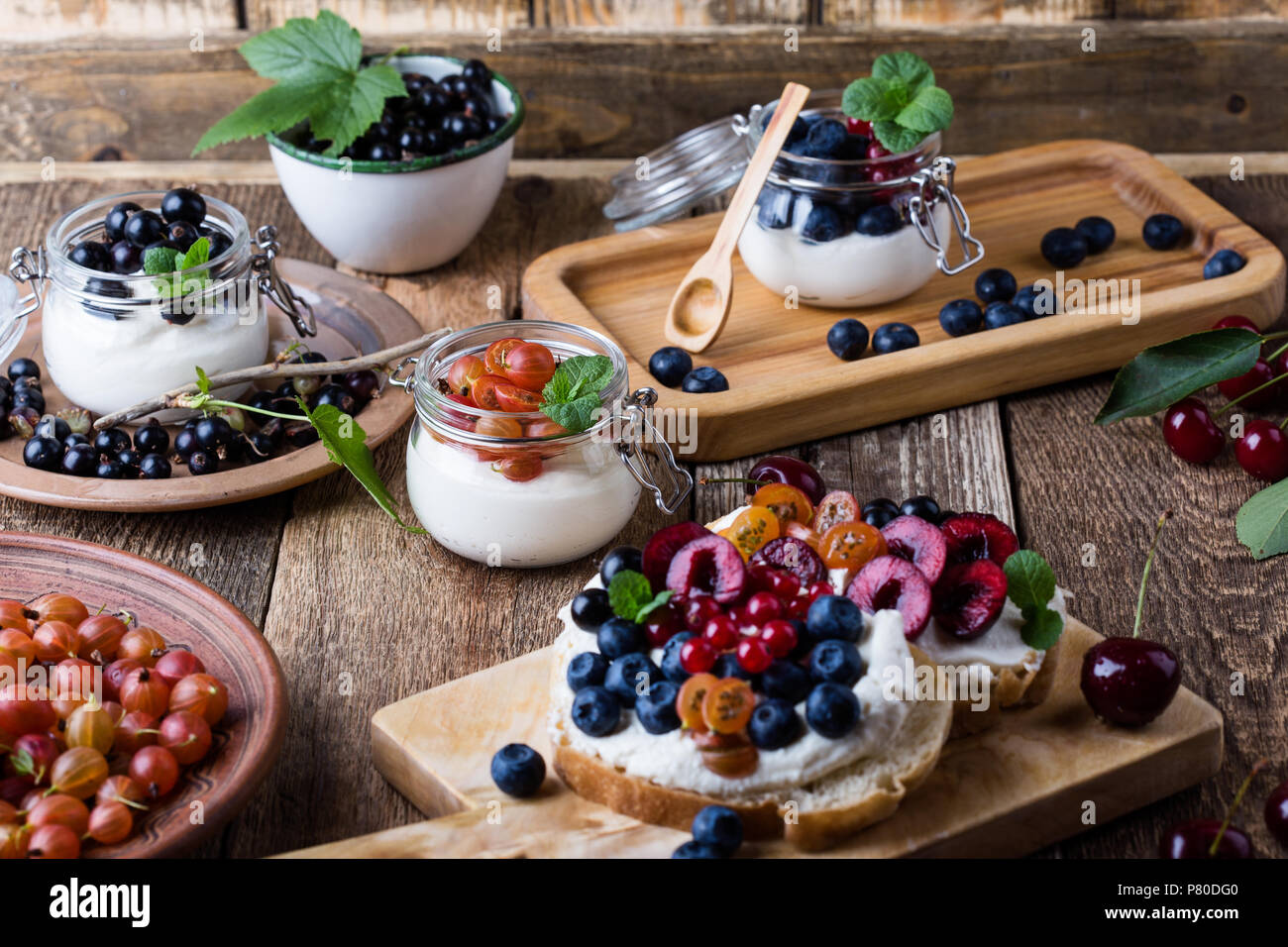 La crema di formaggio panini e cheesecake parfait di color crema con fresca frutta estiva in vaso e sana prima colazione Foto Stock