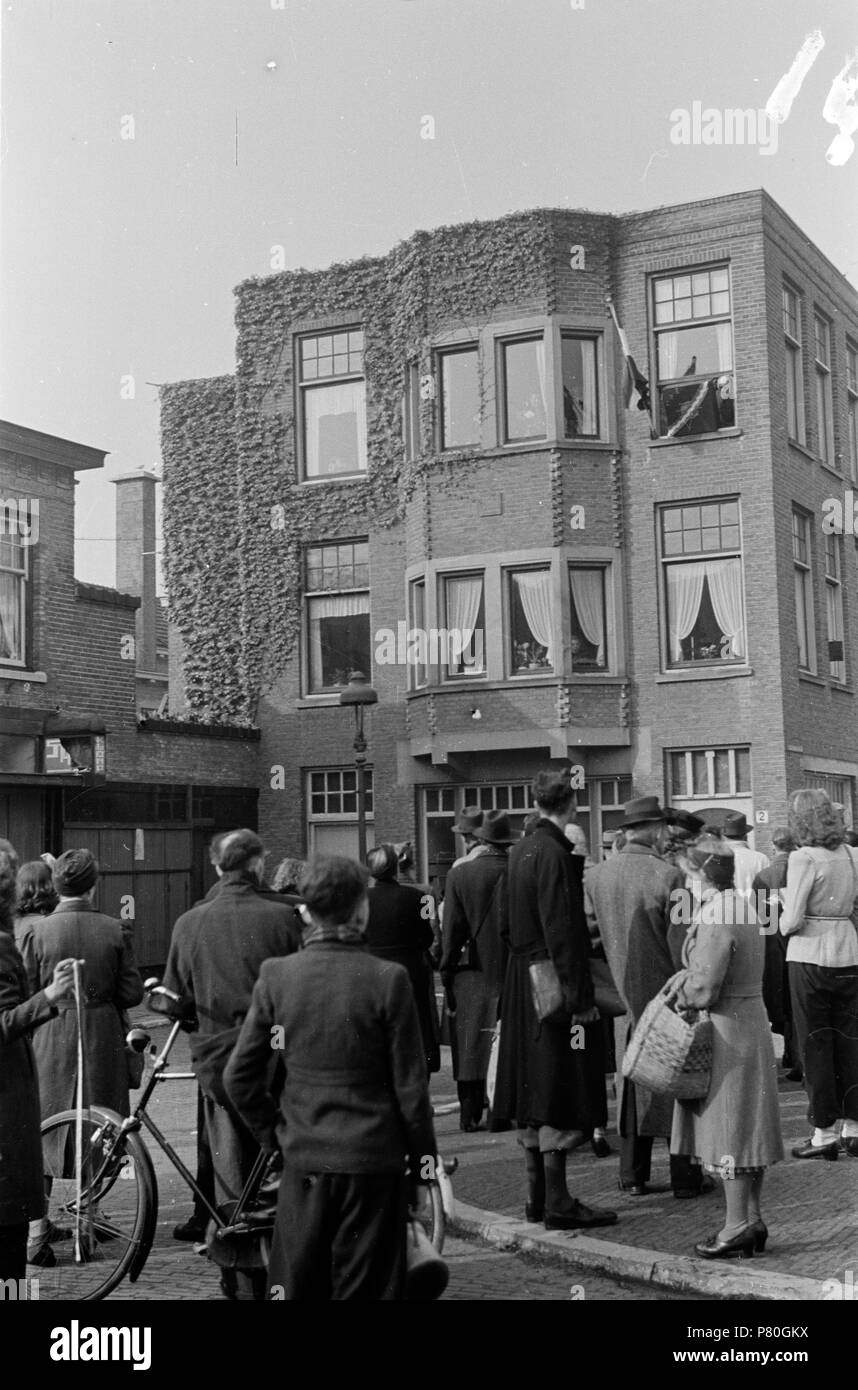 . Huizinga collectie radio - NIOD - 216691. Nederlands: Foto uit de collectie Huizinga van het NIOD. Vol aandacht luisteren mensen op straat naar een Engelstalige nieuwsuitzending, die te horen è via een luidspreker vanuit het venster van een woonhuis, ( raam met de vlag). Menno Huizinga era onderdeel van de Ondergedoken fotocamera en maakte illegaal foto tijdens de bezetting. Dit deed hij hoofdzakelijk in zijn woonplaats Den Haag (L'Aia). Data sconosciuta 38 BC856 HUI-1410 Foto Stock
