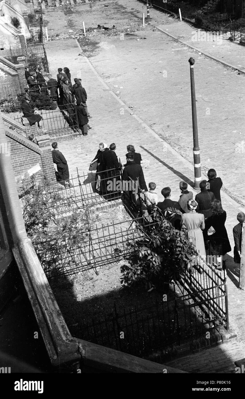 . Huizinga collectie brandstofschaarste - NIOD - 216897. Nederlands: Foto uit de collectie Huizinga van het NIOD. Een groep mensen staat in de Obrechtstraat te wachten op illegaal verkregen sloophout, dat naar beneden wordt gegooid en meteen kijkt uit de politie er niet aan komt. Menno Huizinga era onderdeel van de Ondergedoken fotocamera en maakte illegaal foto tijdens de bezetting. Dit deed hij hoofdzakelijk in zijn woonplaats Den Haag (L'Aia). Data sconosciuta 39 BC856 HUI-1659 Foto Stock