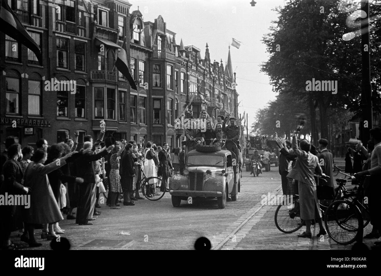 . Huizinga collectie Prinses Irene-brigata - NIOD - 216923. Nederlands: Foto uit de collectie Huizinga van het NIOD. Een uitzinnige menigte begroet te Den Haag de binnenrijdende voertuigen van de Canadese militairen en più tardi van de Prinses Irene-brigata, in het begin van de avond op 8 mei 1945. Menno Huizinga era onderdeel van de Ondergedoken fotocamera en maakte illegaal foto tijdens de bezetting. Dit deed hij hoofdzakelijk in zijn woonplaats Den Haag (L'Aia). N/A 39 BC856 HUI-1687 Foto Stock