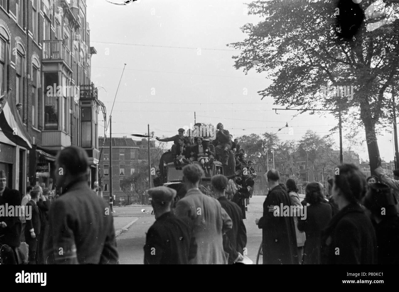 . Huizinga collectie Prinses Irene-brigata - NIOD - 216926. Nederlands: Foto uit de collectie Huizinga van het NIOD. Een uitzinnige menigte op de Hoek van de Groot Hertoginnelaan en de Obrechtstraat te Den Haag begroet de binnenrijdende voertuigen van de Prinses Irene-brigata, in het begin van de avond op 8 mei 1945. Menno Huizinga era onderdeel van de Ondergedoken fotocamera en maakte illegaal foto tijdens de bezetting. Dit deed hij hoofdzakelijk in zijn woonplaats Den Haag (L'Aia). N/A 39 BC856 HUI-1690 Foto Stock