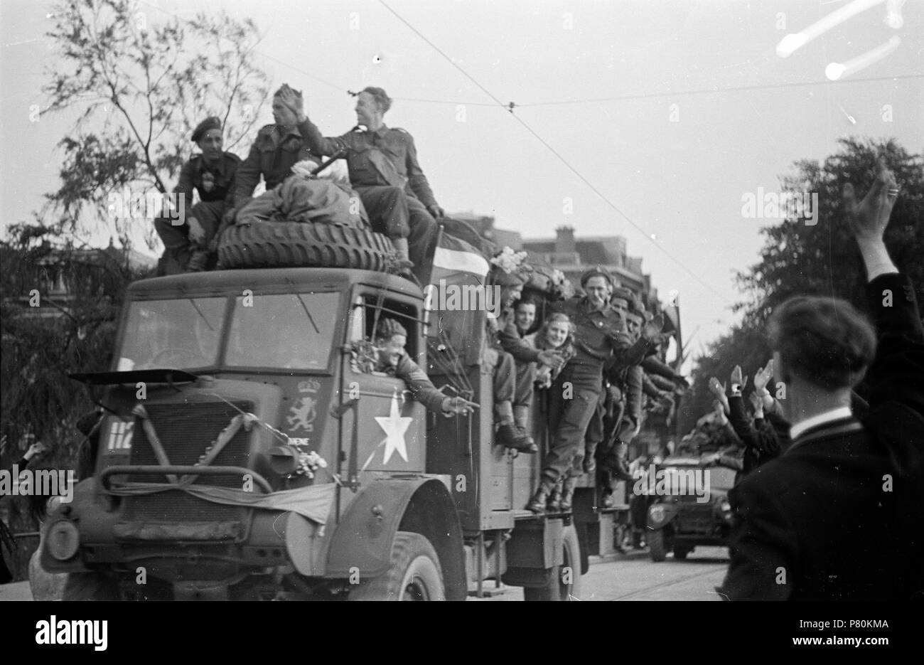 . Huizinga collectie Prinses Irene-brigata - NIOD - 216947. Nederlands: Foto uit de collectie Huizinga van het NIOD. Een uitzinnige menigte begroet de binnenrijdende voertuigen van de Prinses Irene Brigata te Den Haag, op de vroege avondo van 8 mei 1945. Menno Huizinga era onderdeel van de Ondergedoken fotocamera en maakte illegaal foto tijdens de bezetting. Dit deed hij hoofdzakelijk in zijn woonplaats Den Haag (L'Aia). N/A 39 BC856 HUI-1711 Foto Stock
