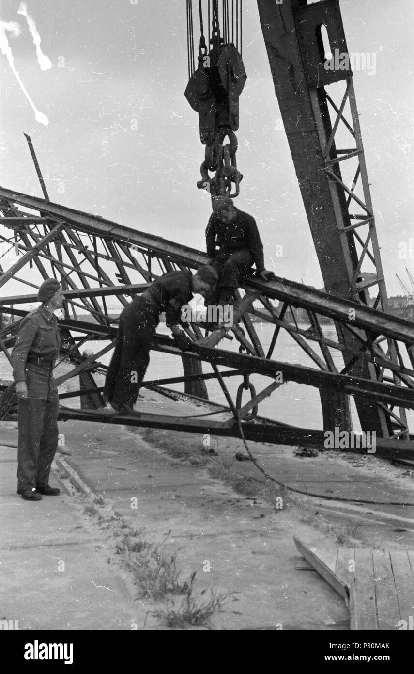 . Huizinga collectie schaarste - NIOD - 217001. Nederlands: Foto uit de collectie Huizinga van het NIOD. Met behulp van een hijskraan trachten militairen de ergste oorlogsschade aan installaties langs het acqua te herstellen. Menno Huizinga era onderdeel van de Ondergedoken fotocamera en maakte illegaal foto tijdens de bezetting. Dit deed hij hoofdzakelijk in zijn woonplaats Den Haag (L'Aia). Data sconosciuta 39 BC856 HUI-1764 Foto Stock