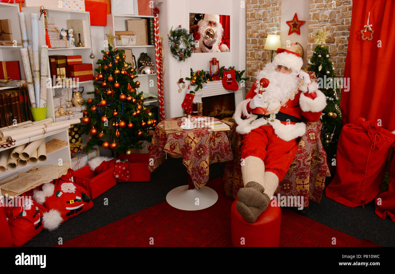 Santa Claus facendo una telefonata a casa nel soggiorno Foto Stock