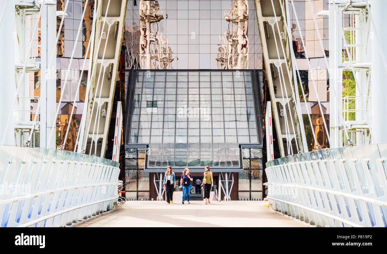 Tre donne parlare e camminare insieme lontano dall'ufficio edificio di più di un ponte a Salford Quays in Manchester eventualmente prendendo una pausa pranzo Foto Stock