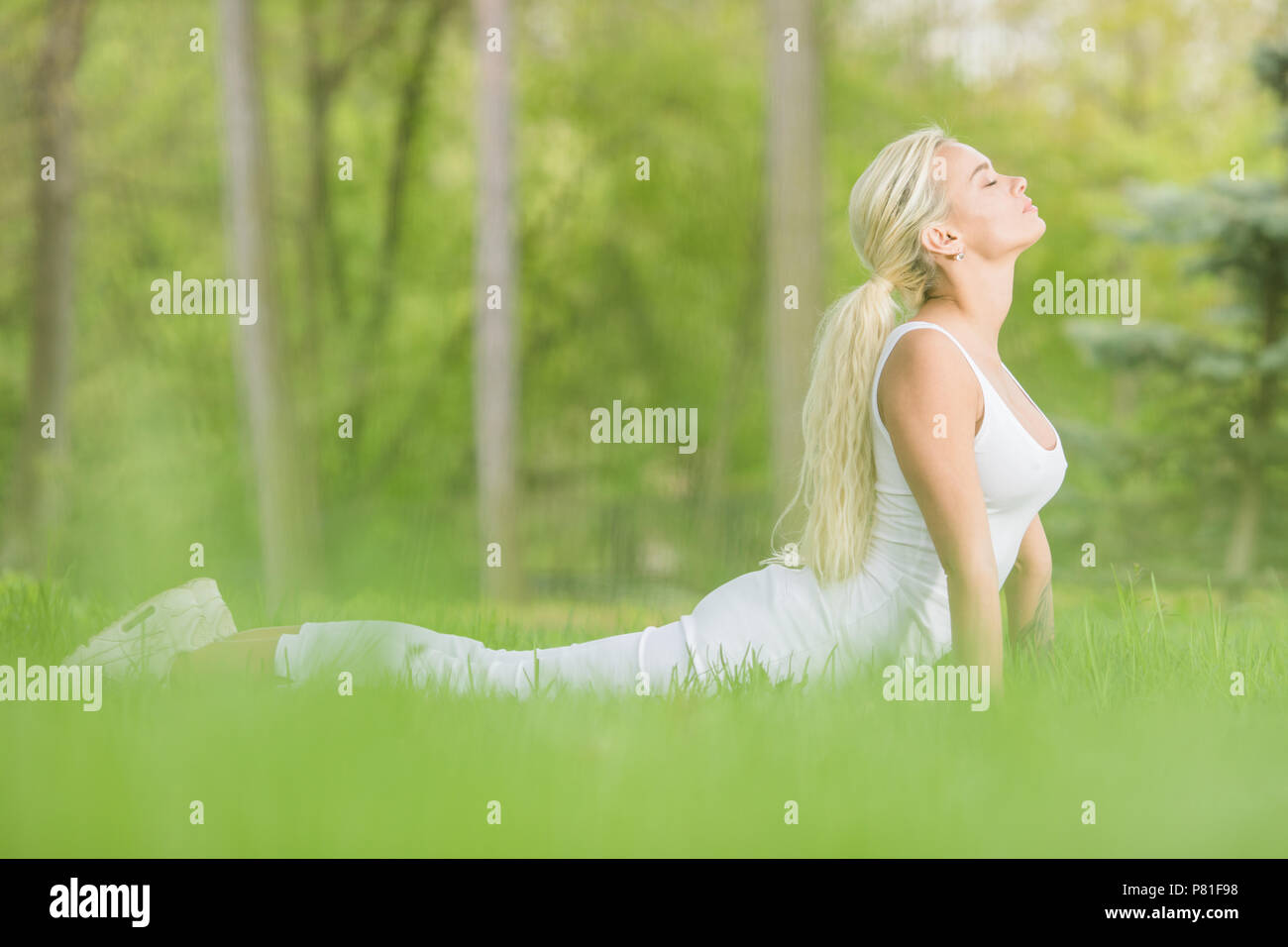 Ragazza giovane facendo cobra asana esercizi yoga nel Parco di primavera Foto Stock